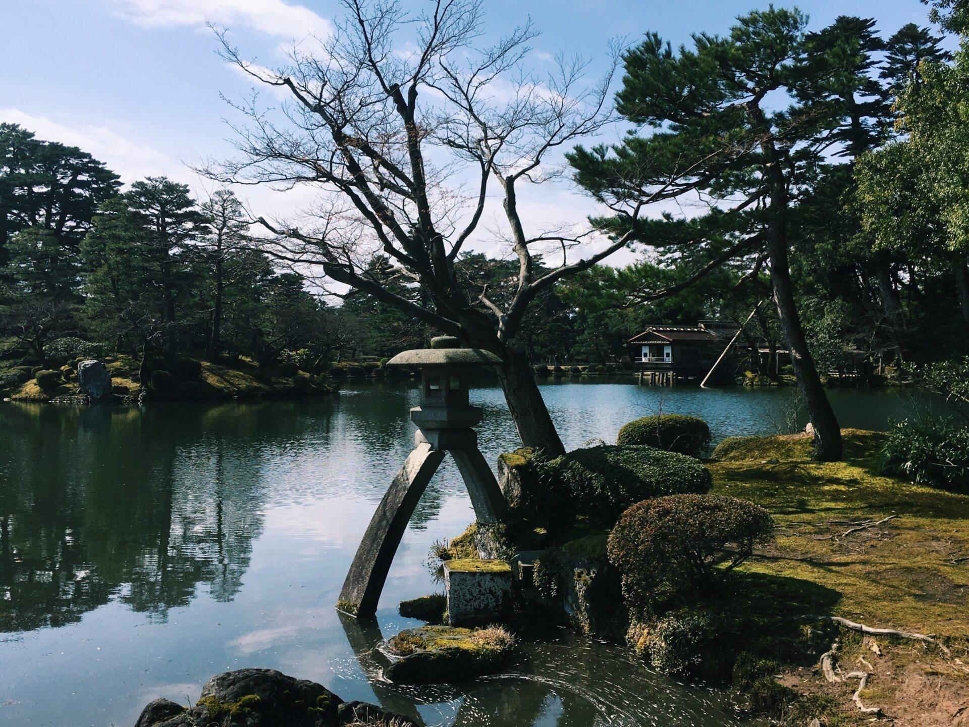 Ein traditioneller japanischer Garten mit einem ruhigen Teich, alten Bäumen und einem Teehaus am Wasser