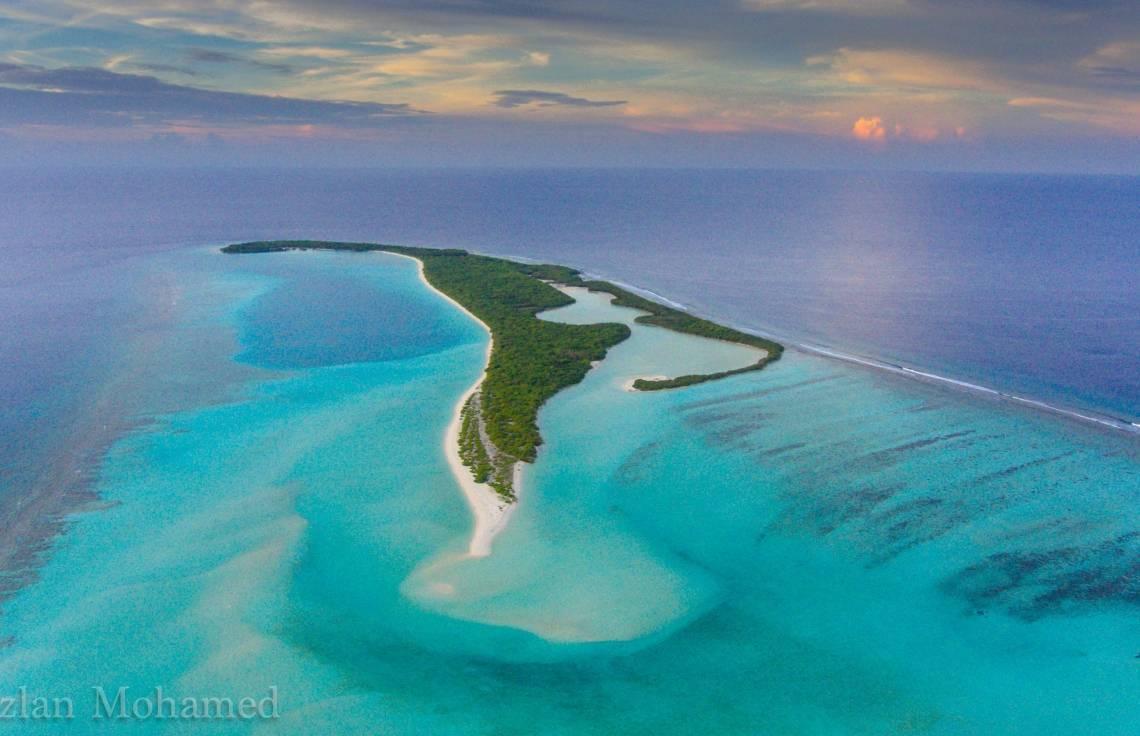 Vista aerea di un’isola tropicale con laguna turchese, spiagge di sabbia bianca e fitta foresta verde