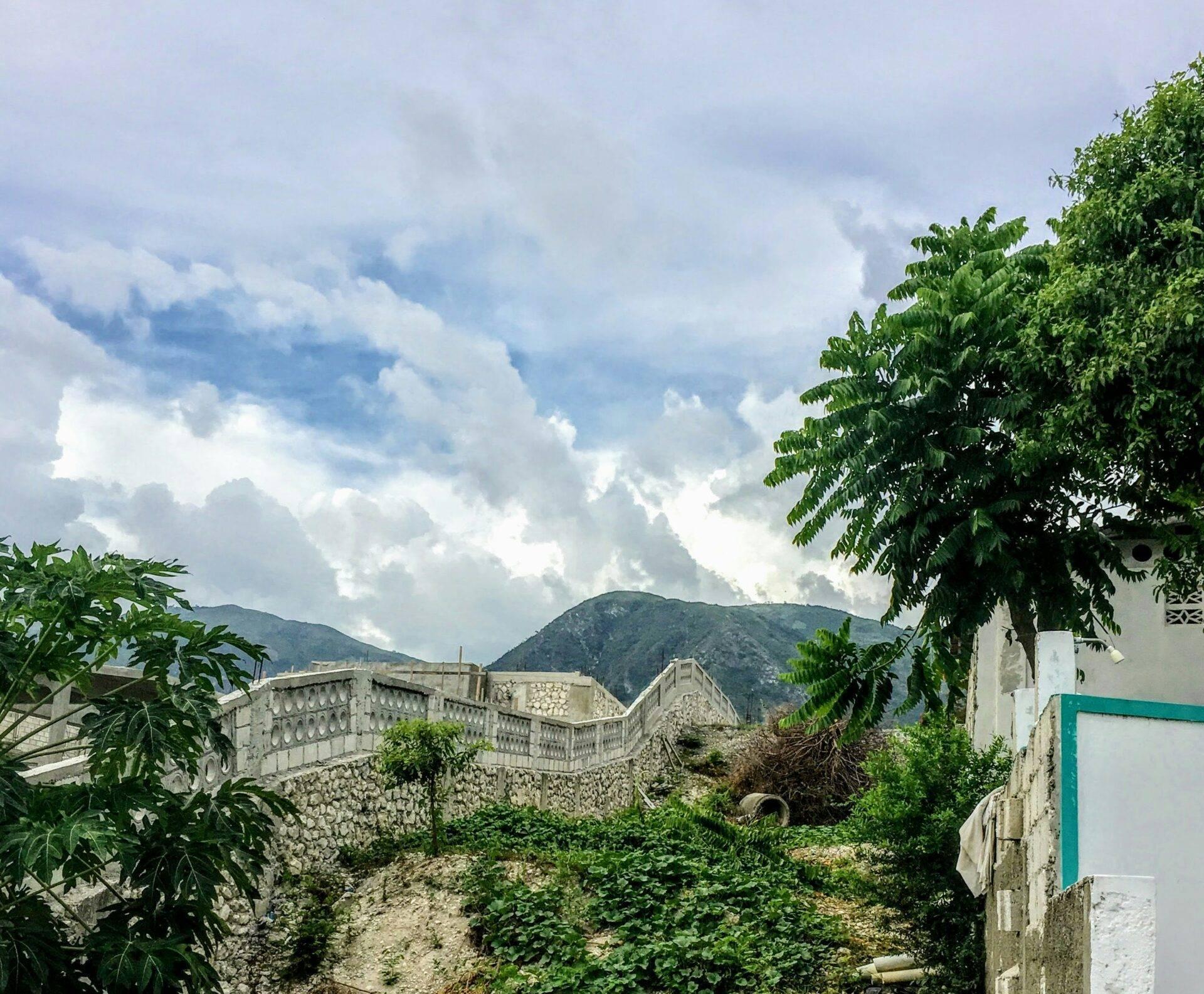 Vista de ruinas de una fortification de piedra con montañas boscosas al fondo bajo un cielo nublado