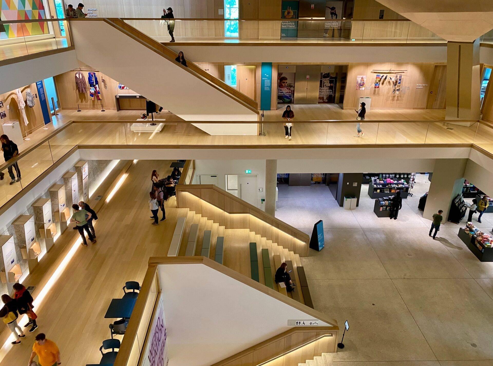 Luftaufnahme eines modernen Kulturgebäudes mit mehreren Etagen, Treppen, fließenden Besucherströmen und gut beleuchteten Ausstellungsbereichen