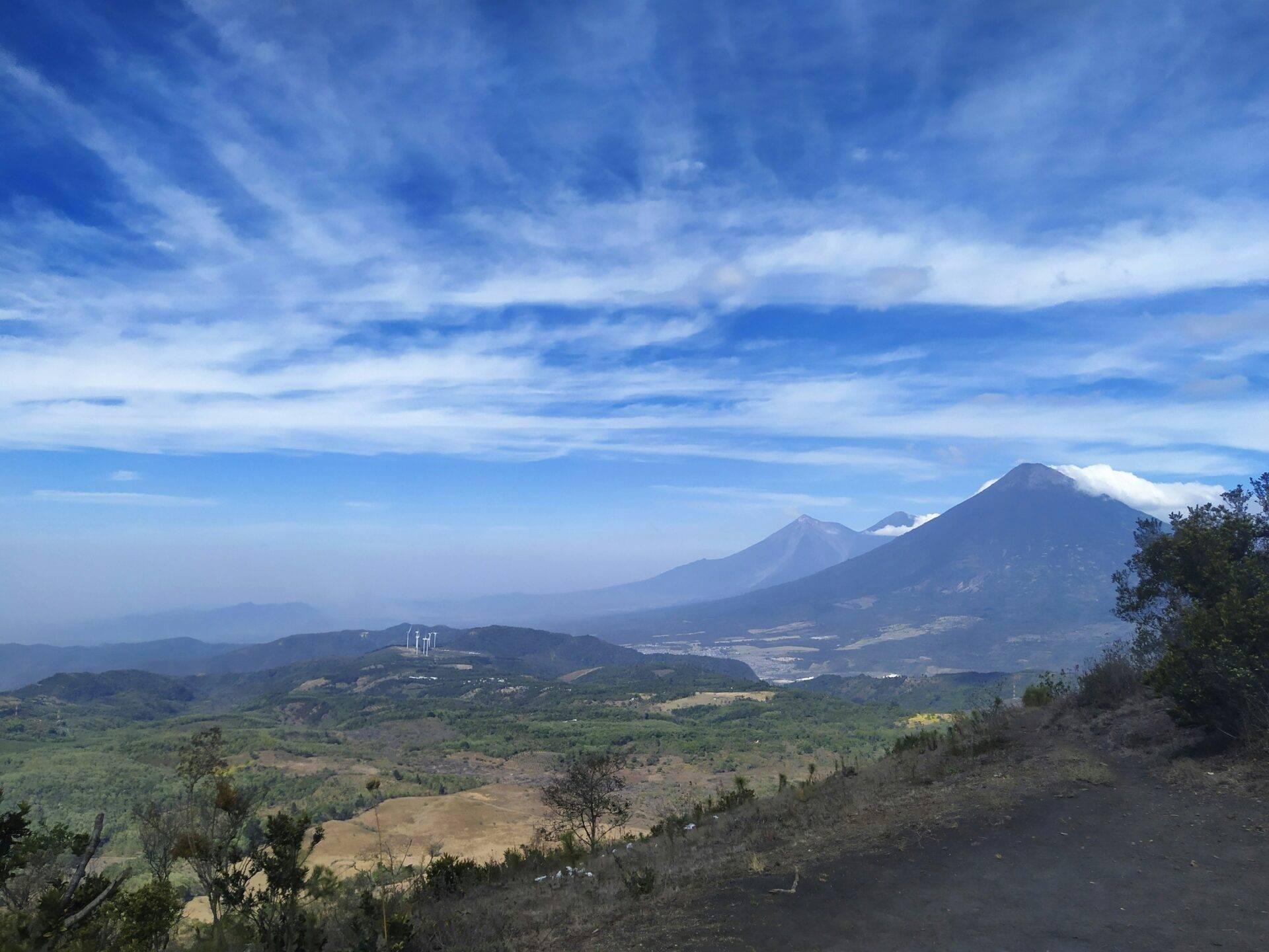 Panoramablick auf majestätische Vulkane, die ein grünes Tal mit Feldern überragen