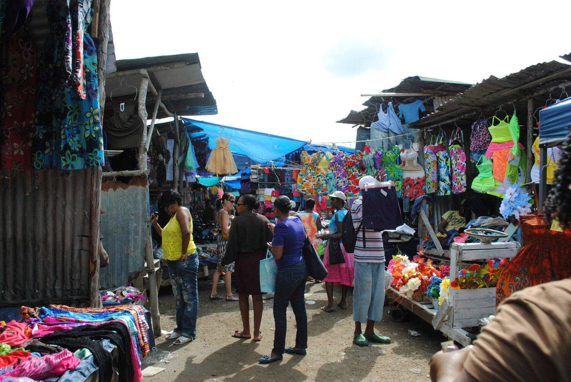 Ein farbenfroher Freiluftmarkt mit leuchtenden Kleidungsstücken und Textilien, Besucher schlendern zwischen den Ständen