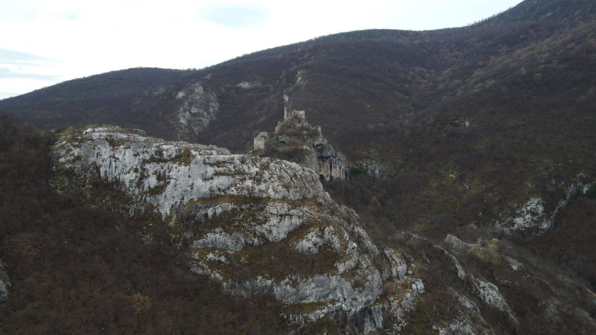 Ruinen einer mittelalterlichen Burg auf einem Kalkfelsen, die ein bewaldetes Gebirgstal überragt