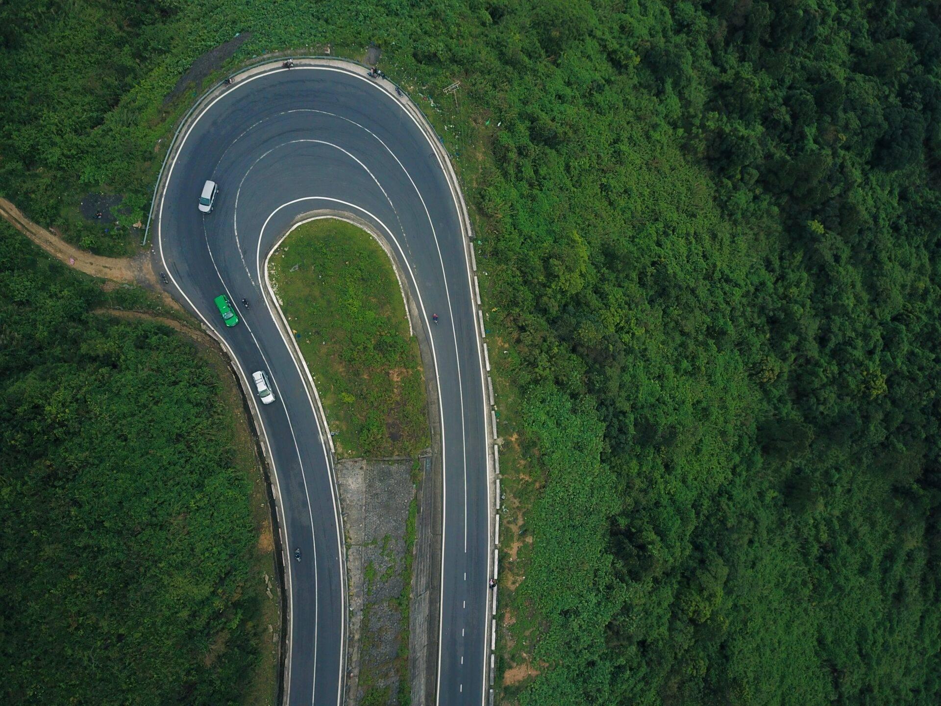 Vista aérea de una carretera en horquilla atravesando un bosque denso y exuberante