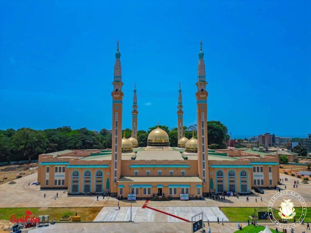 Una grande moschea moderna con cupole dorate e quattro minareti sotto un cielo azzurro terso