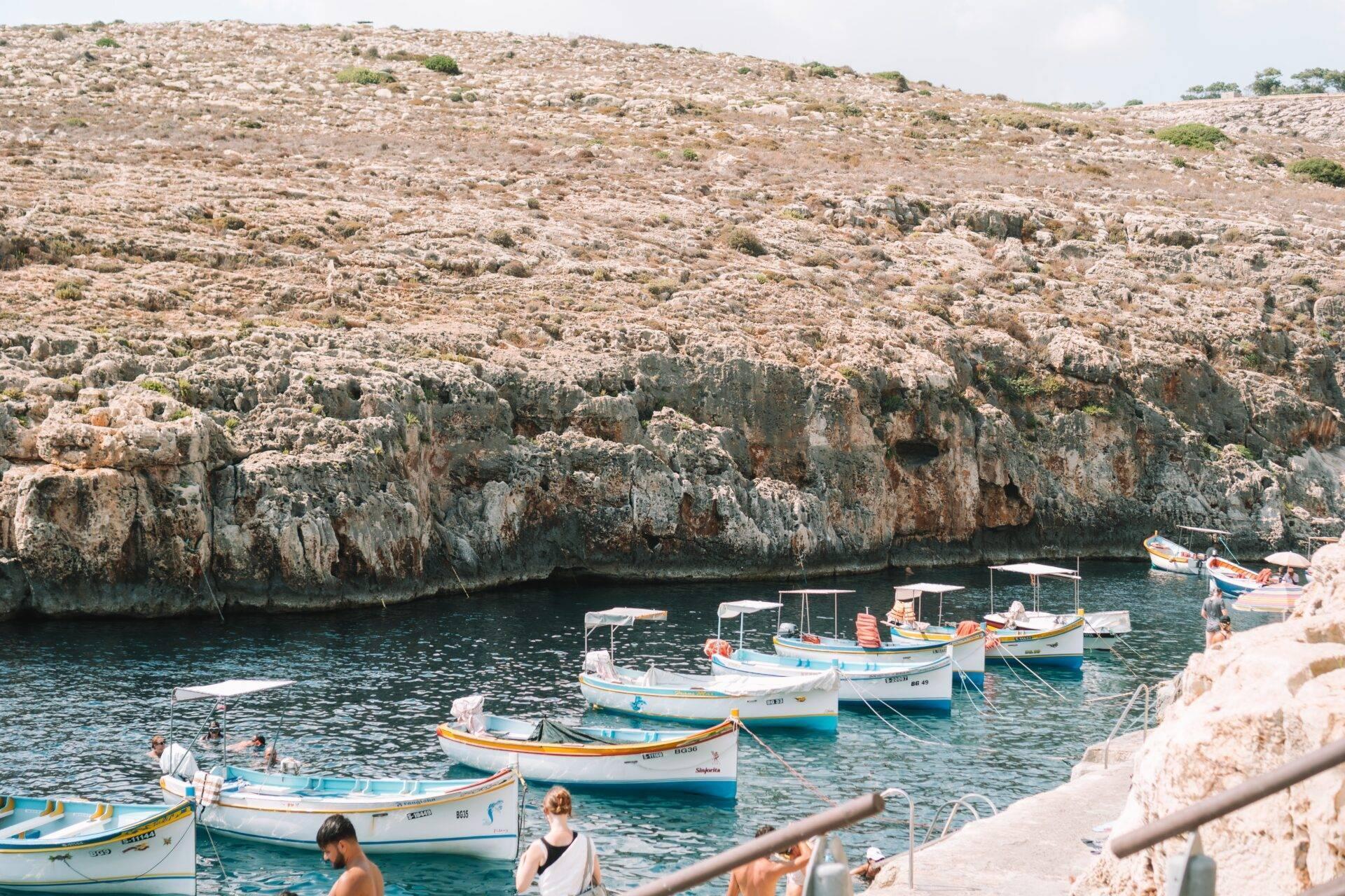 Colourful fishing boats moored in a small Mediterranean cove with steep limestone cliffs