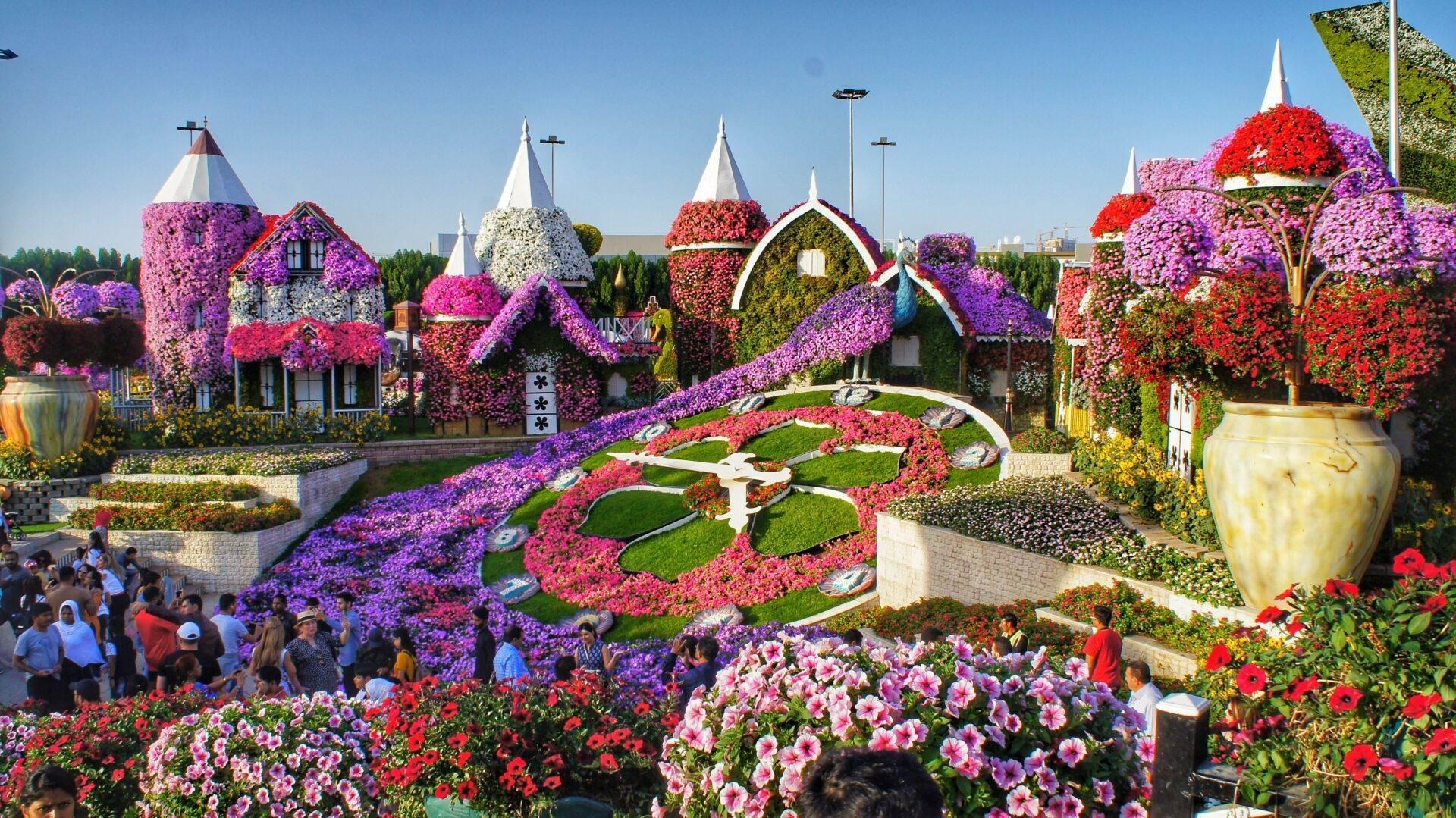 Spektakulärer Blumenpark mit blumengeschmückten Gebäuden in Millionen bunter Farben und Besuchern, die die Installationen bewundern