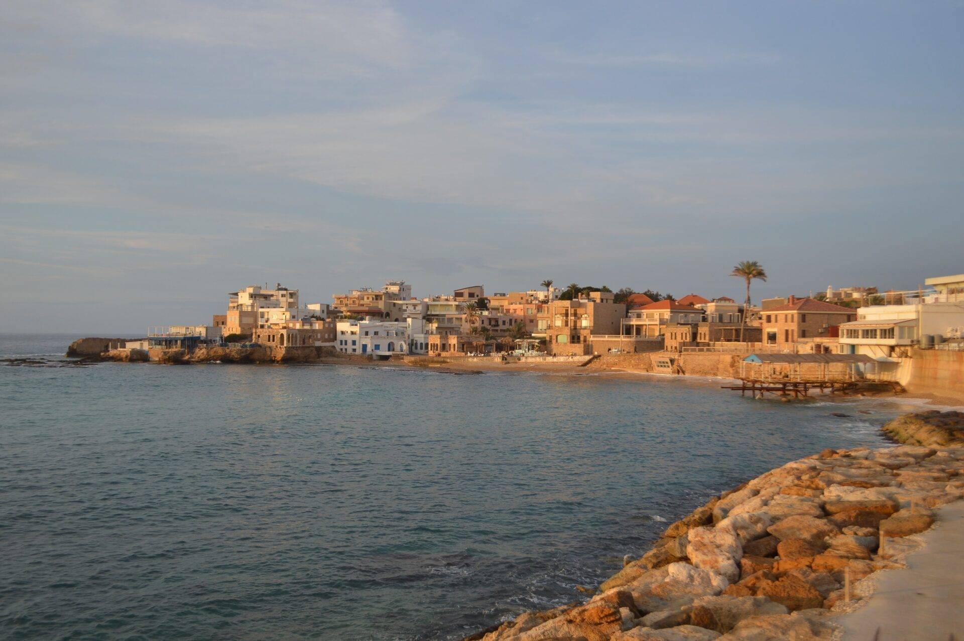 Vista costera de un pueblo mediterráneo con casas de colores construidas directamente sobre la orilla rocosa