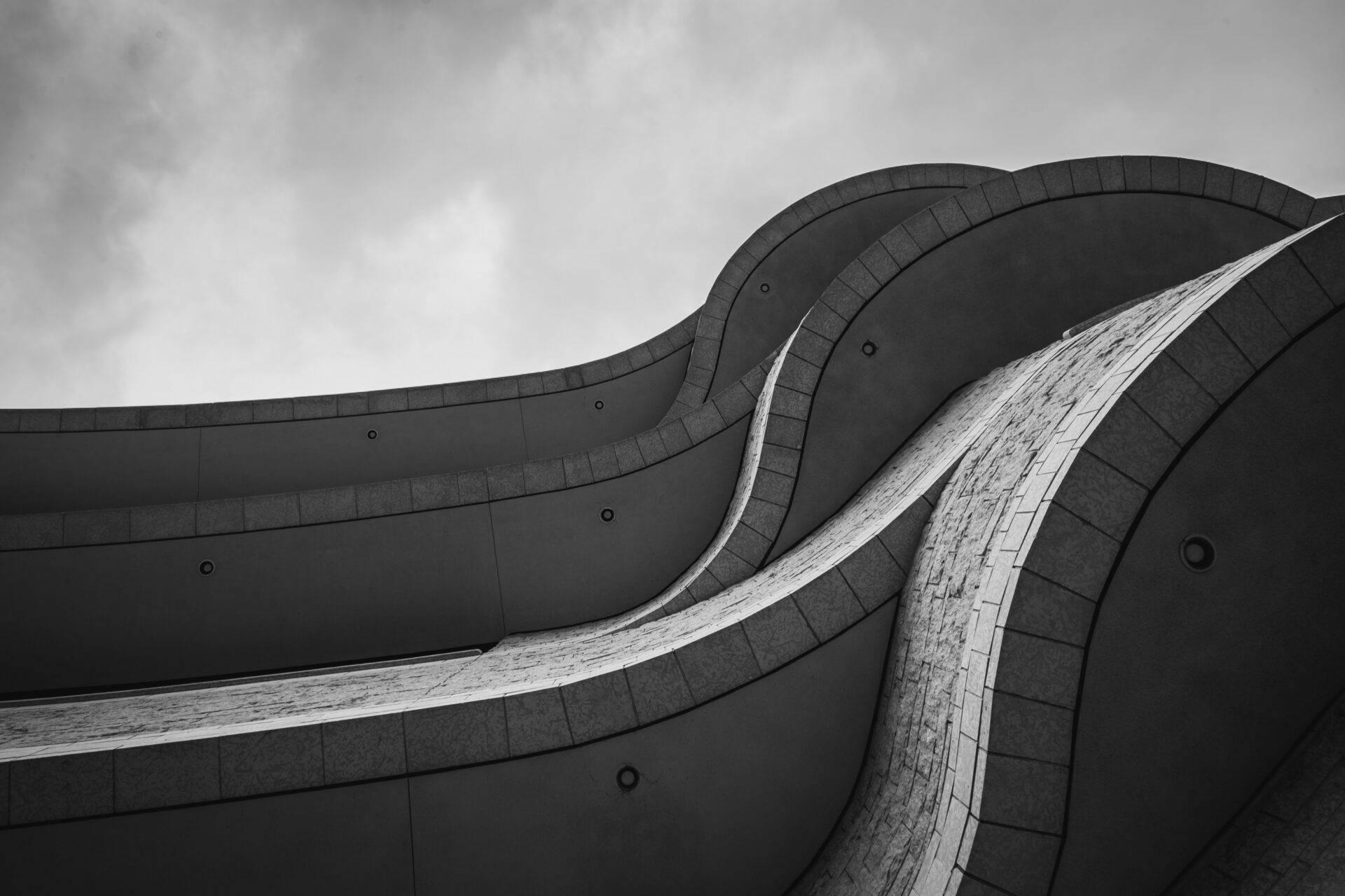 Architektonisches Detail eines modernen Gebäudes in Schwarz-Weiß mit geschwungenen Linien und Kachelverkleidung