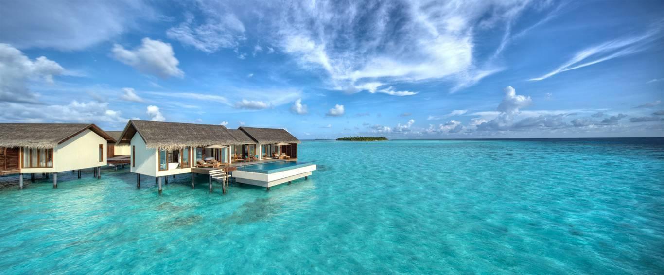 Bungalow di lusso sull’acqua con piscina in un’acqua turchese cristallina sotto un cielo blu
