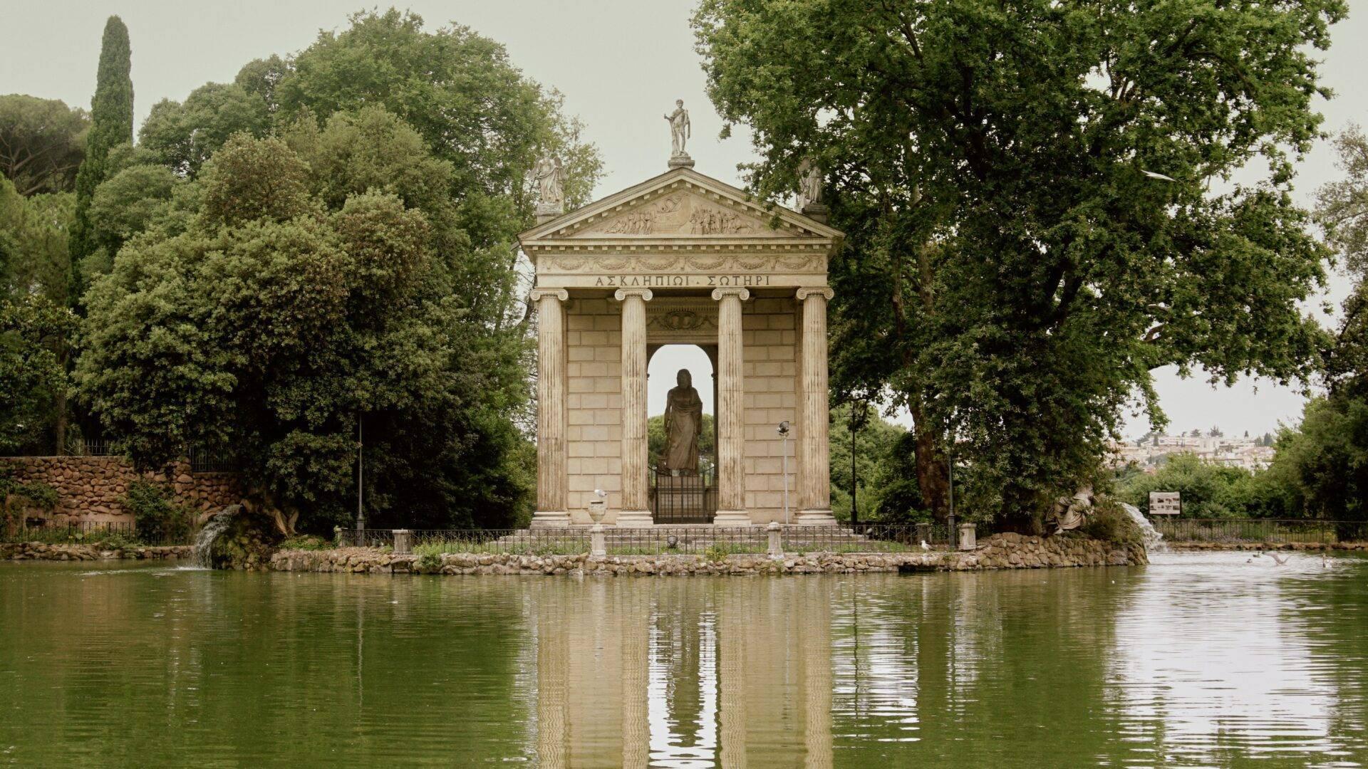 A neoclassical temple with white columns standing on a riverbank, surrounded by lush vegetation