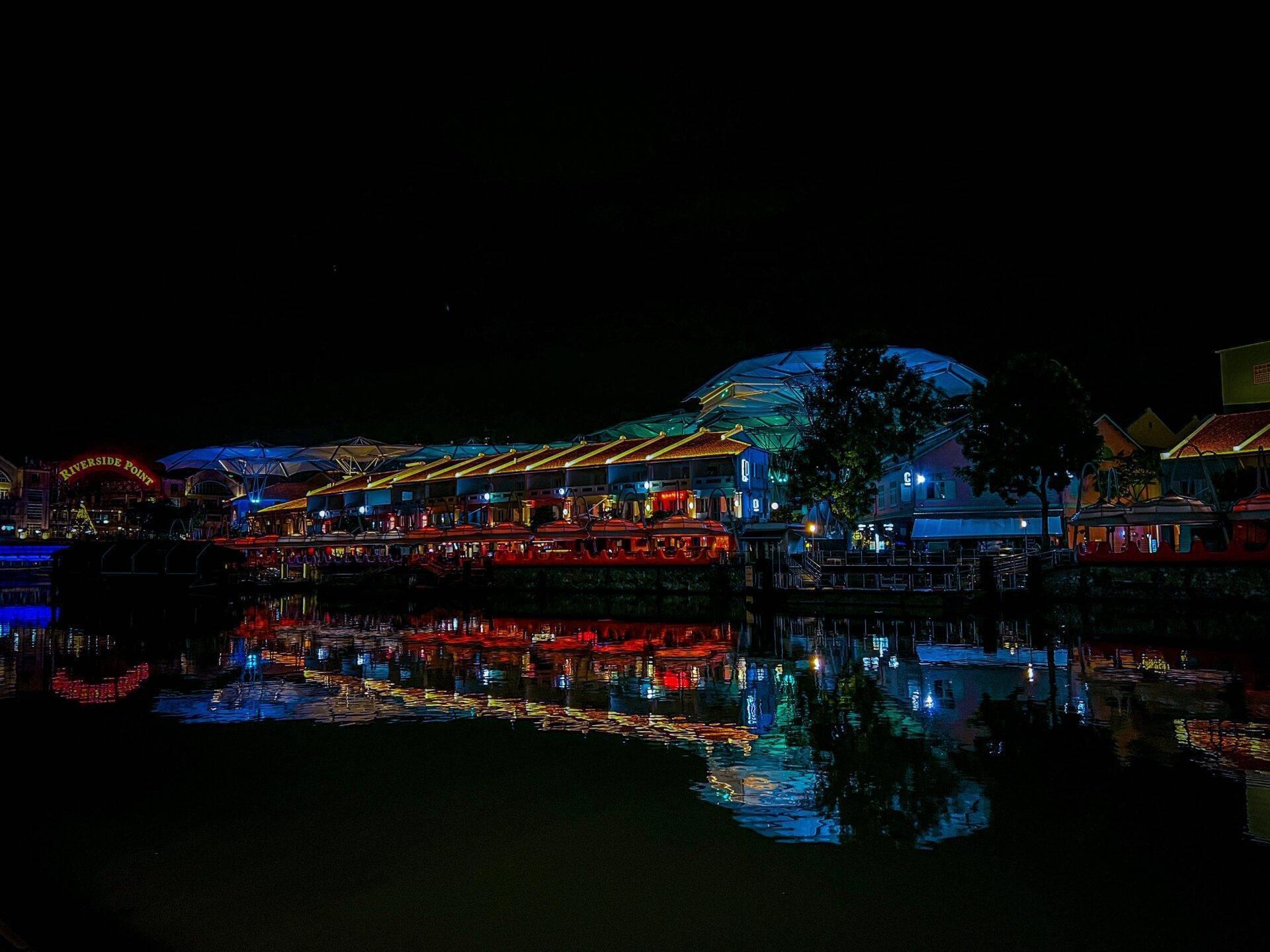 Riverside Point bei Nacht mit blauen und roten beleuchteten Strukturen, die sich im Wasser spiegeln