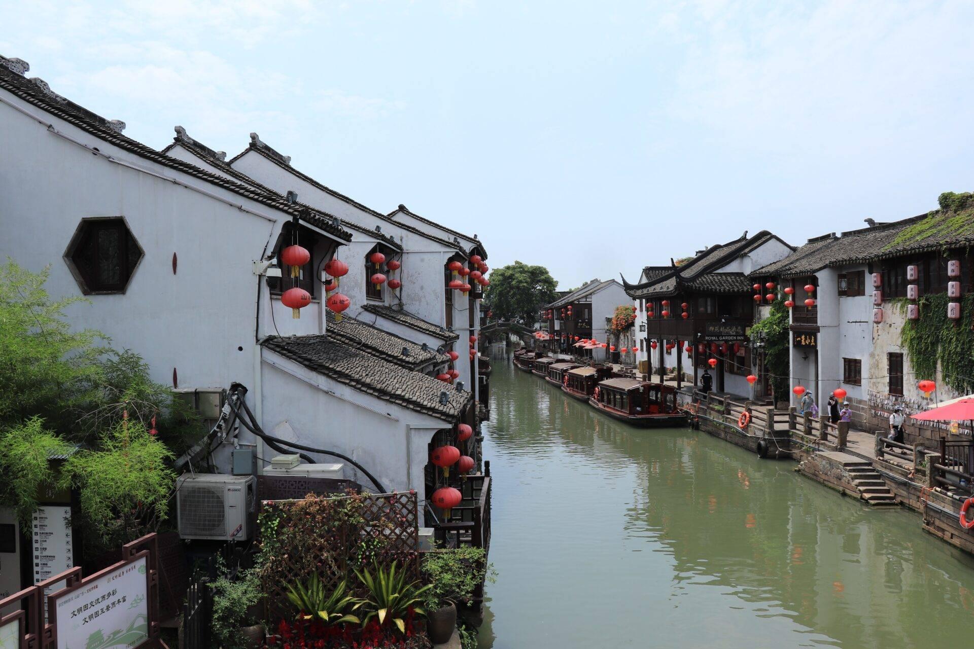 Antico villaggio cinese con canale, architettura tradizionale bianca e nera, lanterne rosse e barche turistiche