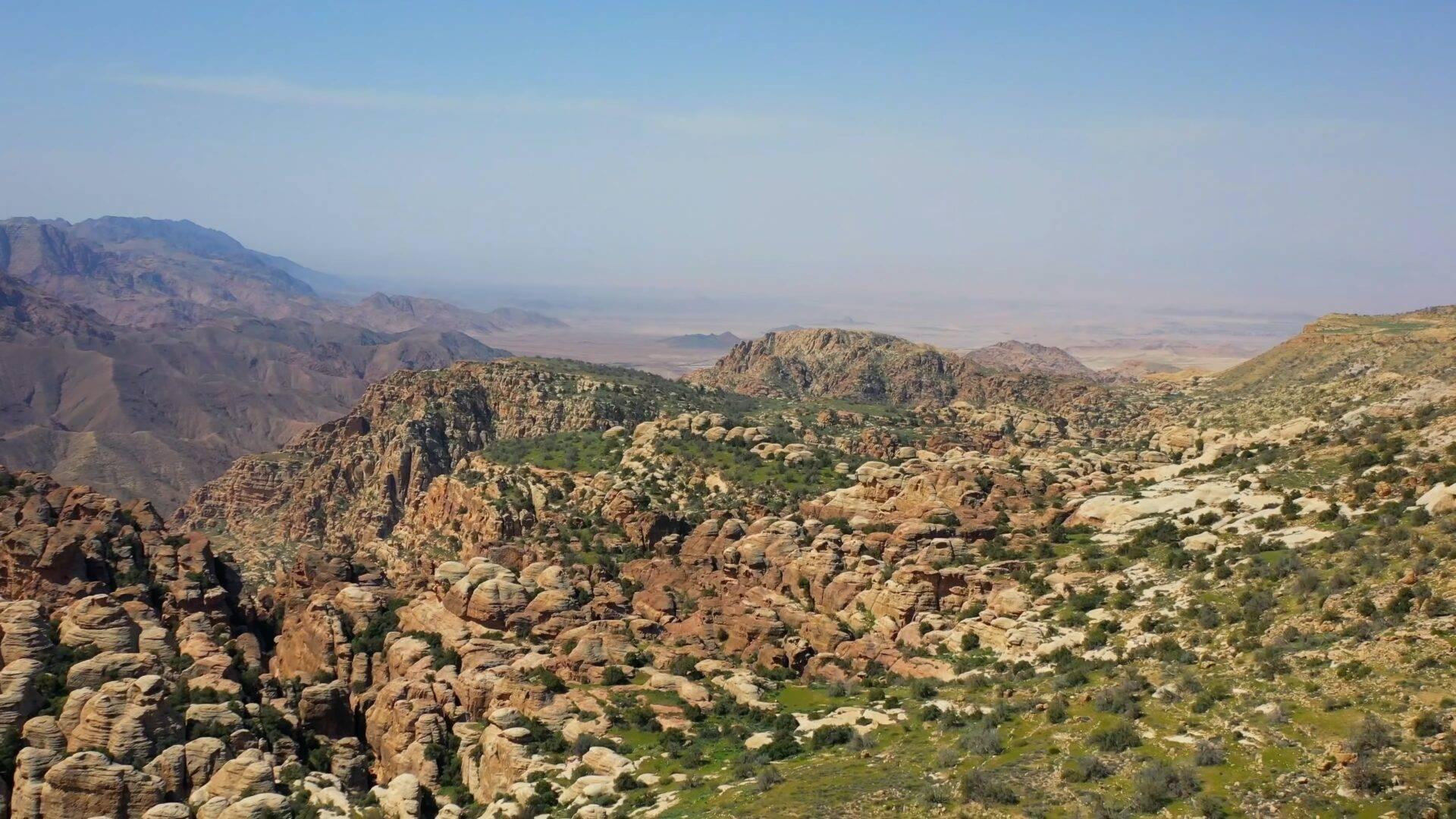 Paisaje montañoso árido con formaciones rocosas espectaculares y valles verdes encajados entre las cimas