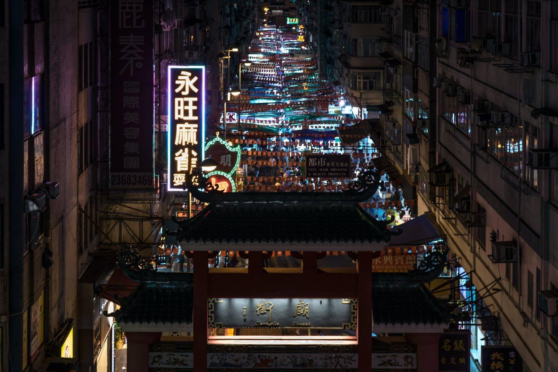 Vista notturna di una strada commerciale asiatica animata con tempio tradizionale e neon colorati