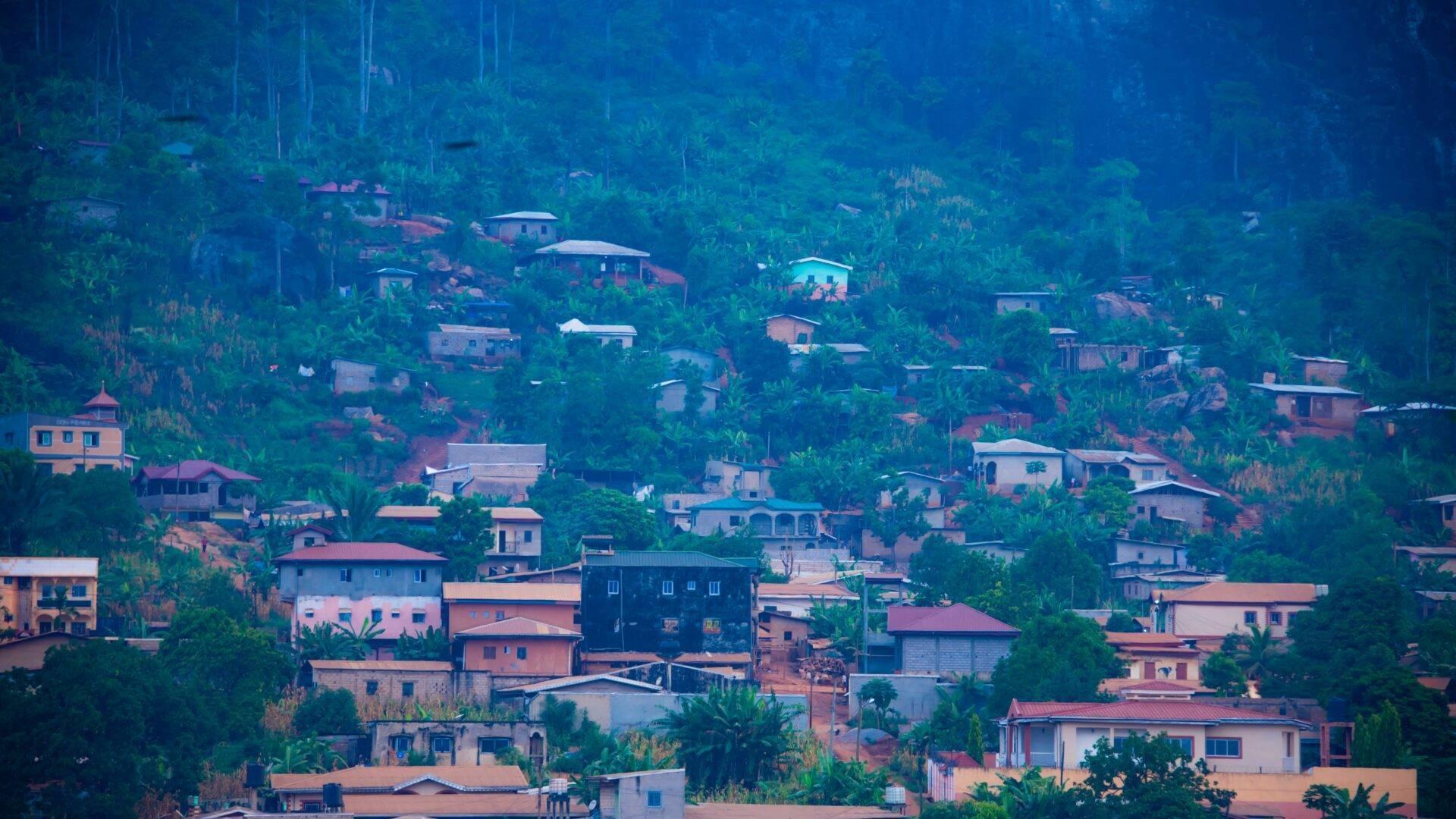 Vista aérea de un pueblo de montaña con casas de colores dispersas entre densa vegetación tropical
