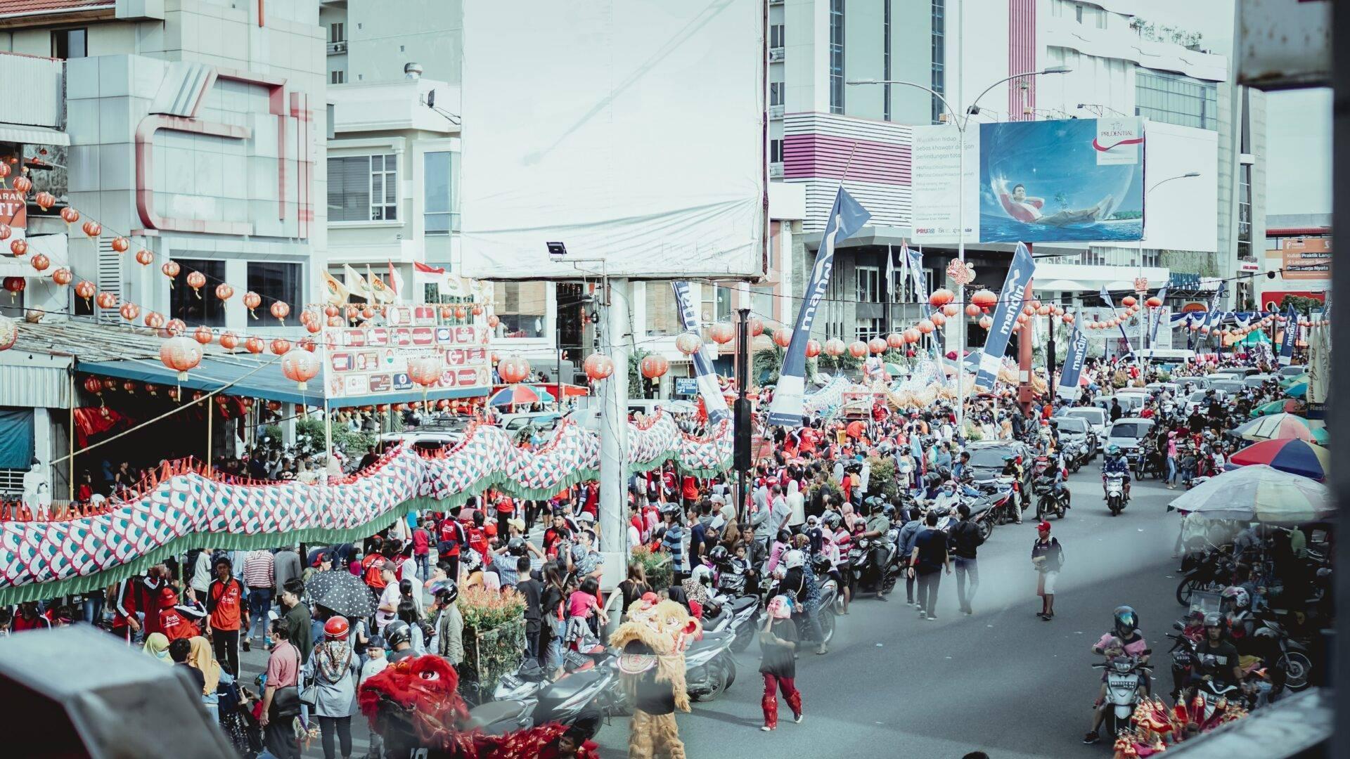 Strada urbana affollata decorata con lanterne rosse e bandiere durante una festa in Indonesia