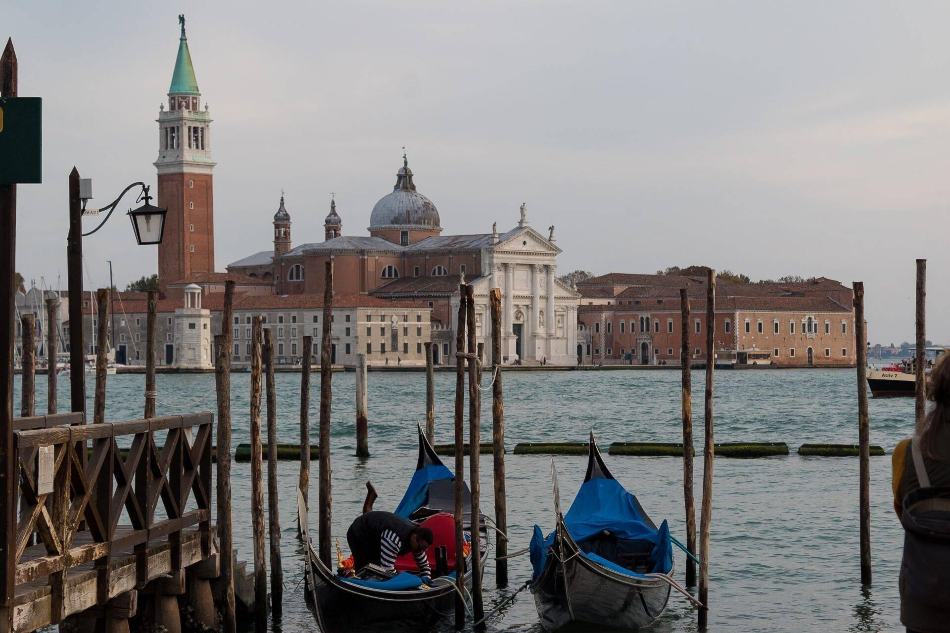 Due gondole ormeggiate davanti all’isola di San Giorgio Maggiore a Venezia, con i suoi edifici storici e il caratteristico campanile