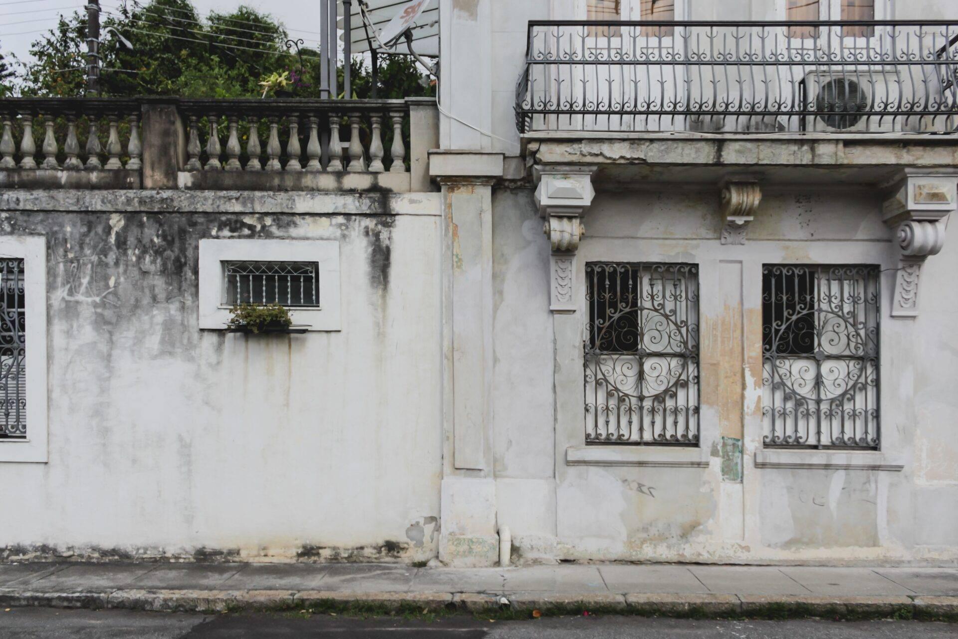 Verwitterte Kolonialfassade mit schmiedeeisernem Balkon und Ziertüren in einer gepflasterten Straße einer brasilianischen Kolonialstadt