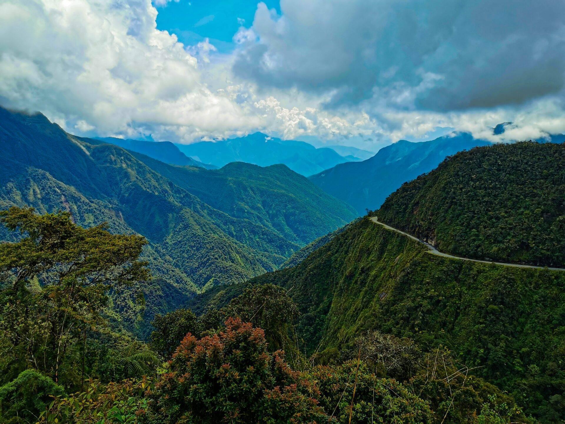 Catena montuosa densamente boscosa con strada tortuosa e cielo nuvoloso, paesaggio montuoso tropicale