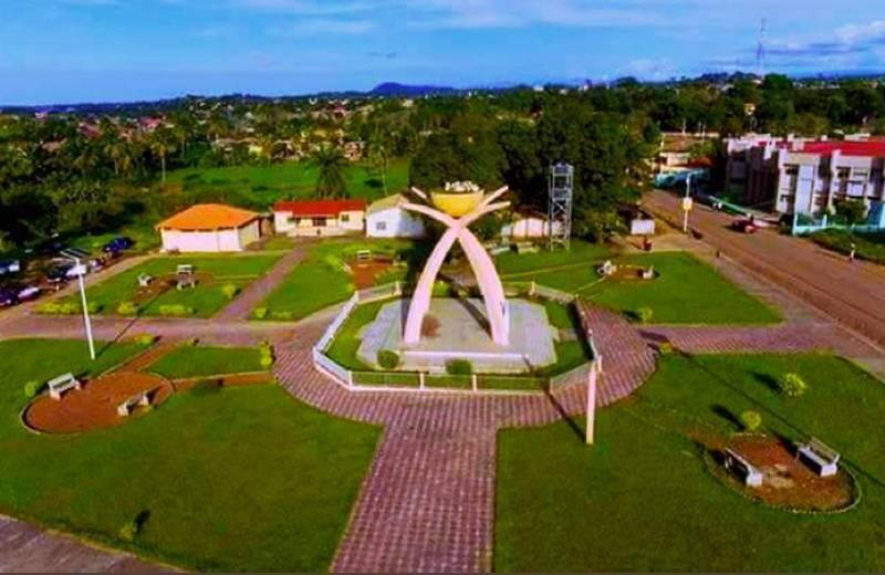 Vista aerea di una piazza pubblica con monumento centrale ad arco, edifici colorati e aree verdi in Guinea