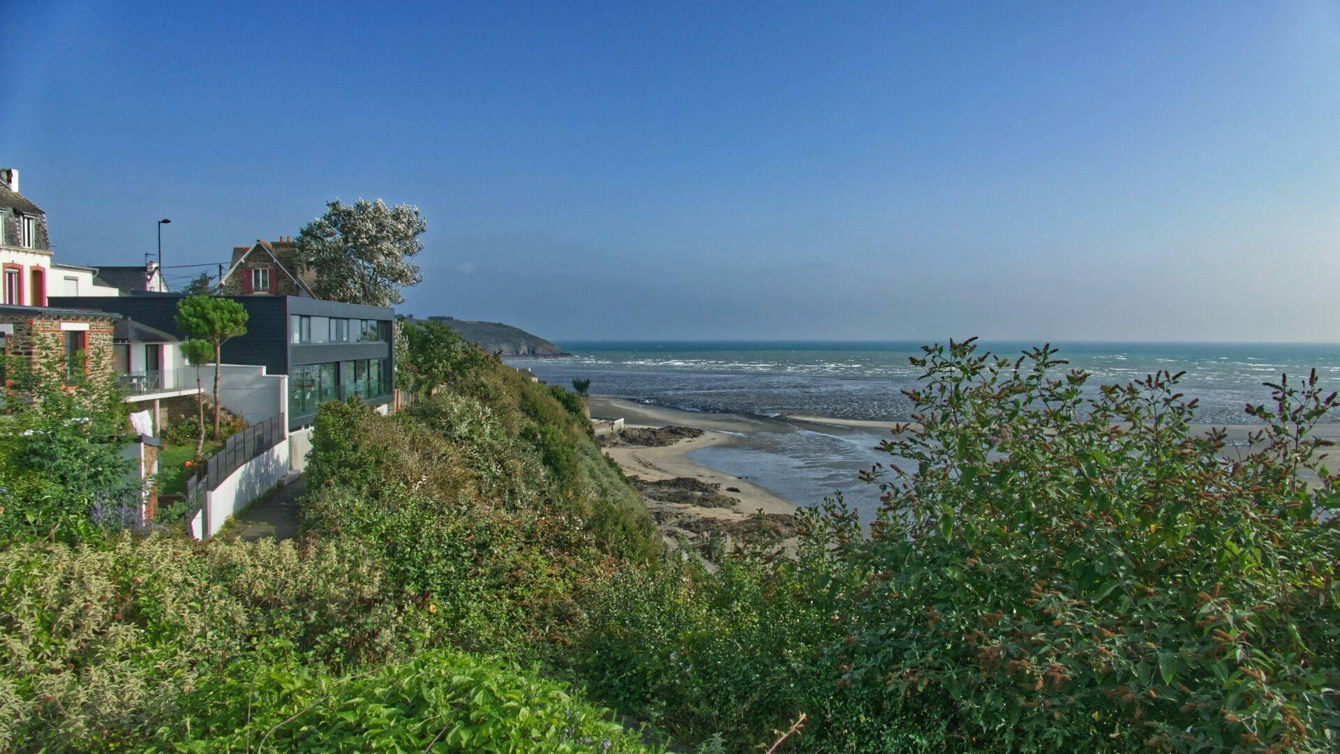 Casas costeras modernas y tradicionales sobre una playa rocosa y el mar bajo un cielo azul despejado