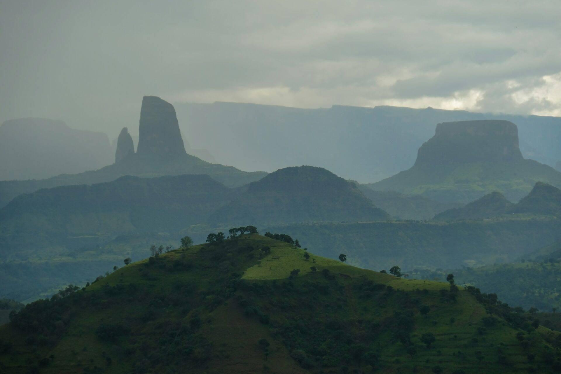 Massive rock formations and verdant mountain plateaus overlooking a misty valley in Ethiopia