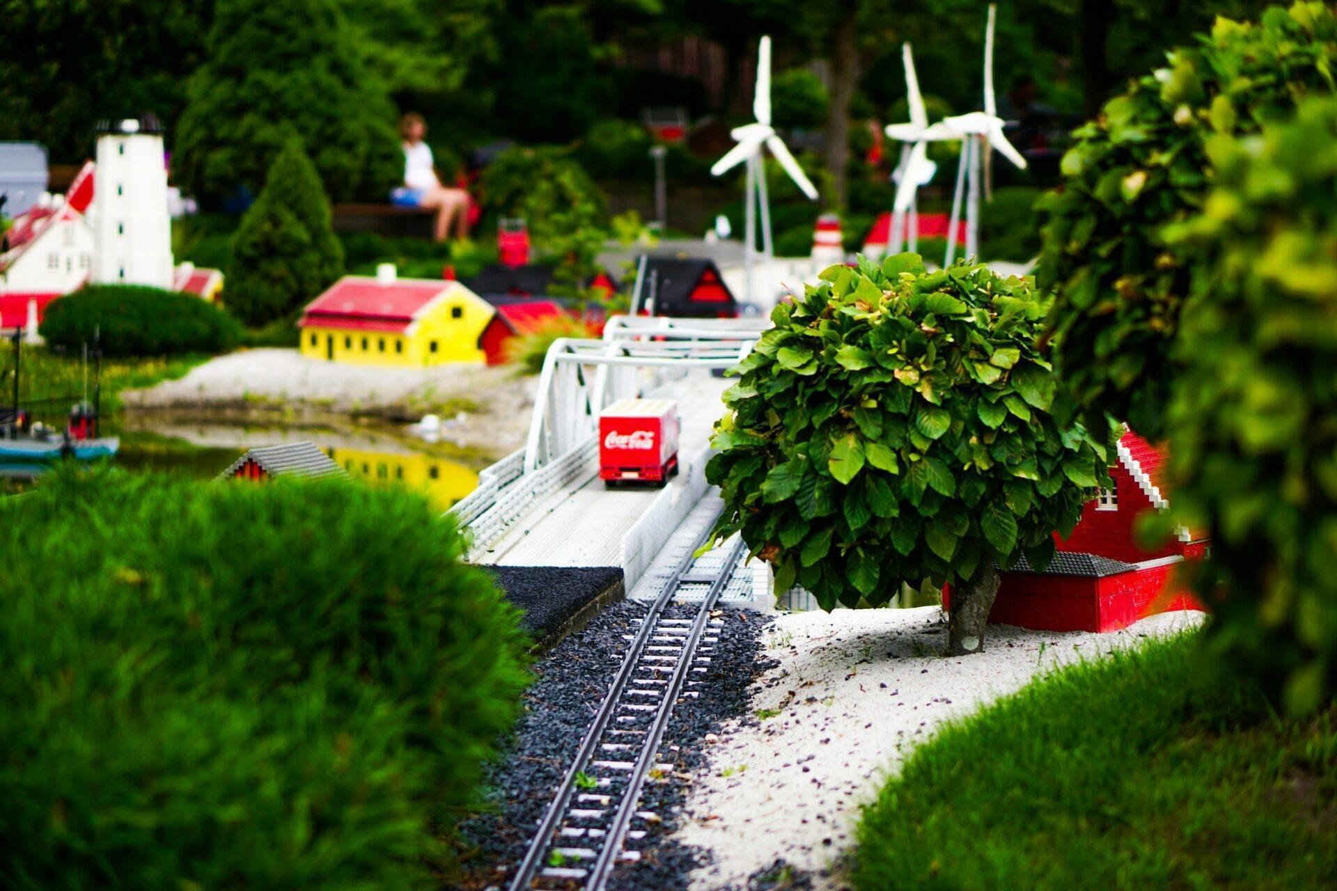 Miniatura di un villaggio danese con treno rosso, case colorate, pale eoliche bianche e vegetazione lussureggiante