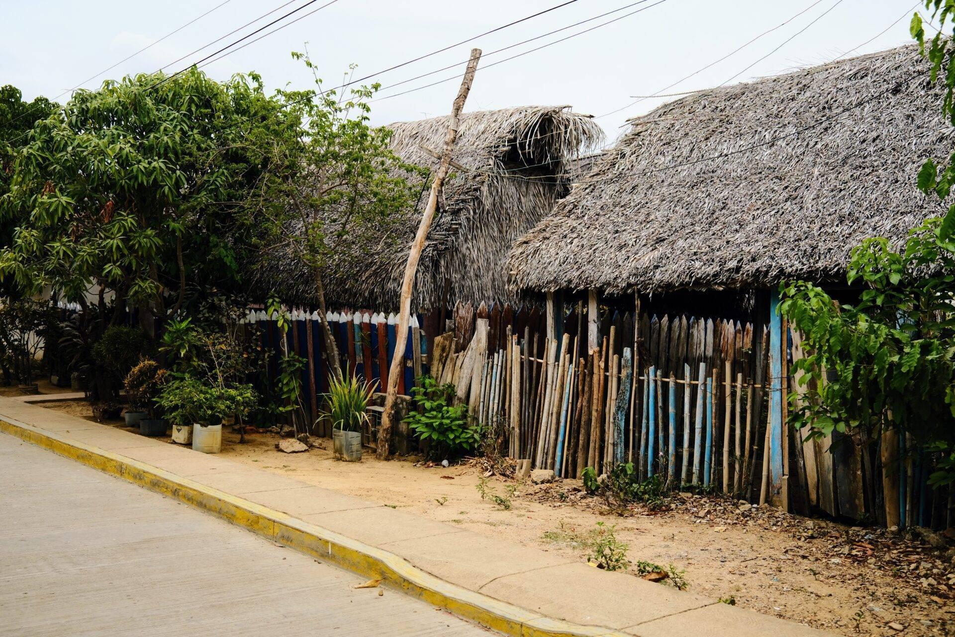 Casa tradicional con paredes de paja y empalizada de madera en un pueblo costero colombiano
