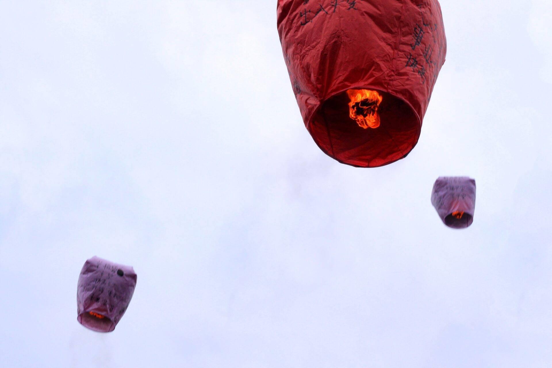 Lanterne volanti rosse e viola si alzano nel cielo al crepuscolo durante una celebrazione tradizionale