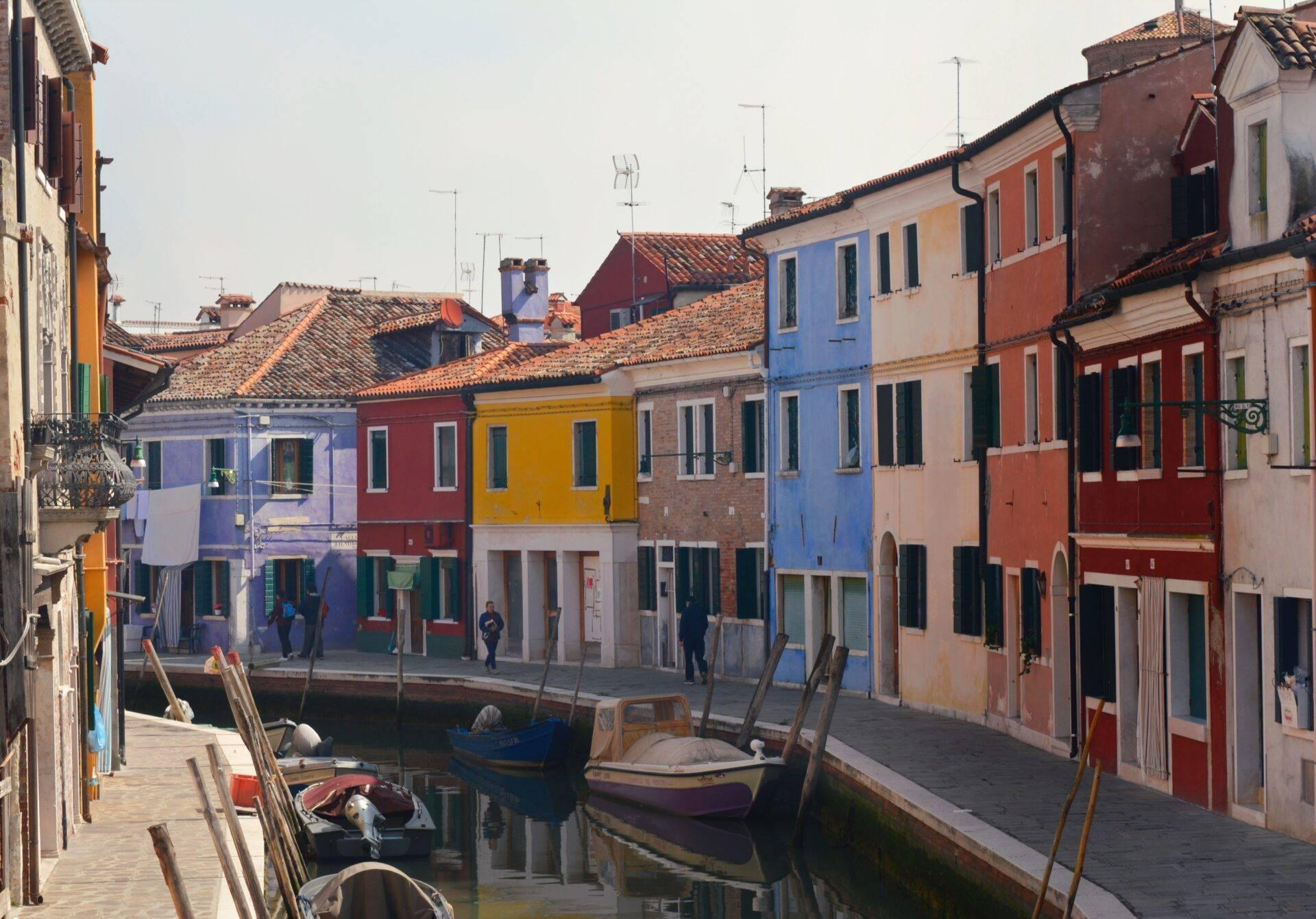 Brightly painted houses lining a canal with fishing boats moored alongside