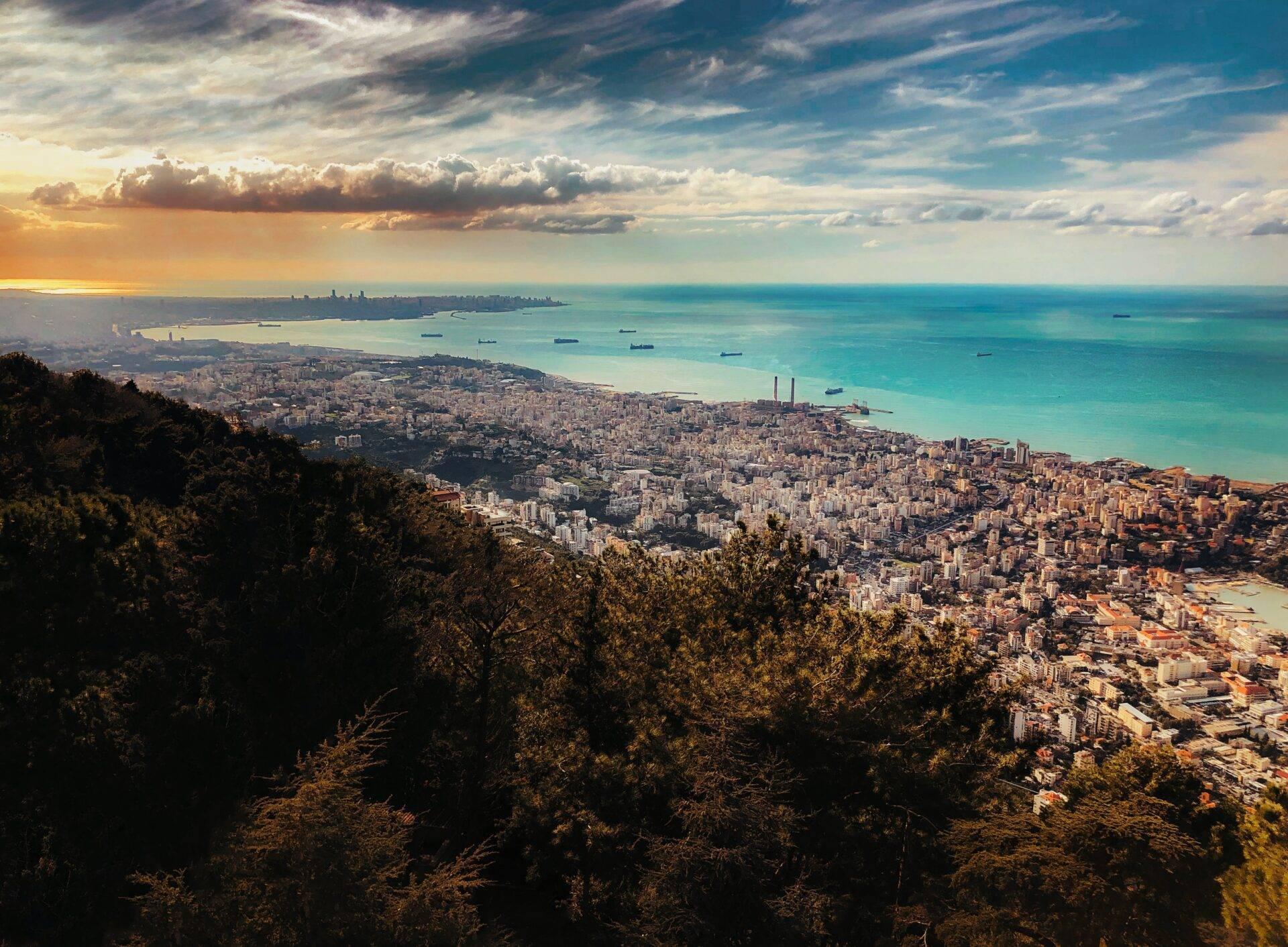Vista panorámica de una ciudad costera mediterránea densamente construida con bahía turquesa y barcos a lo lejos