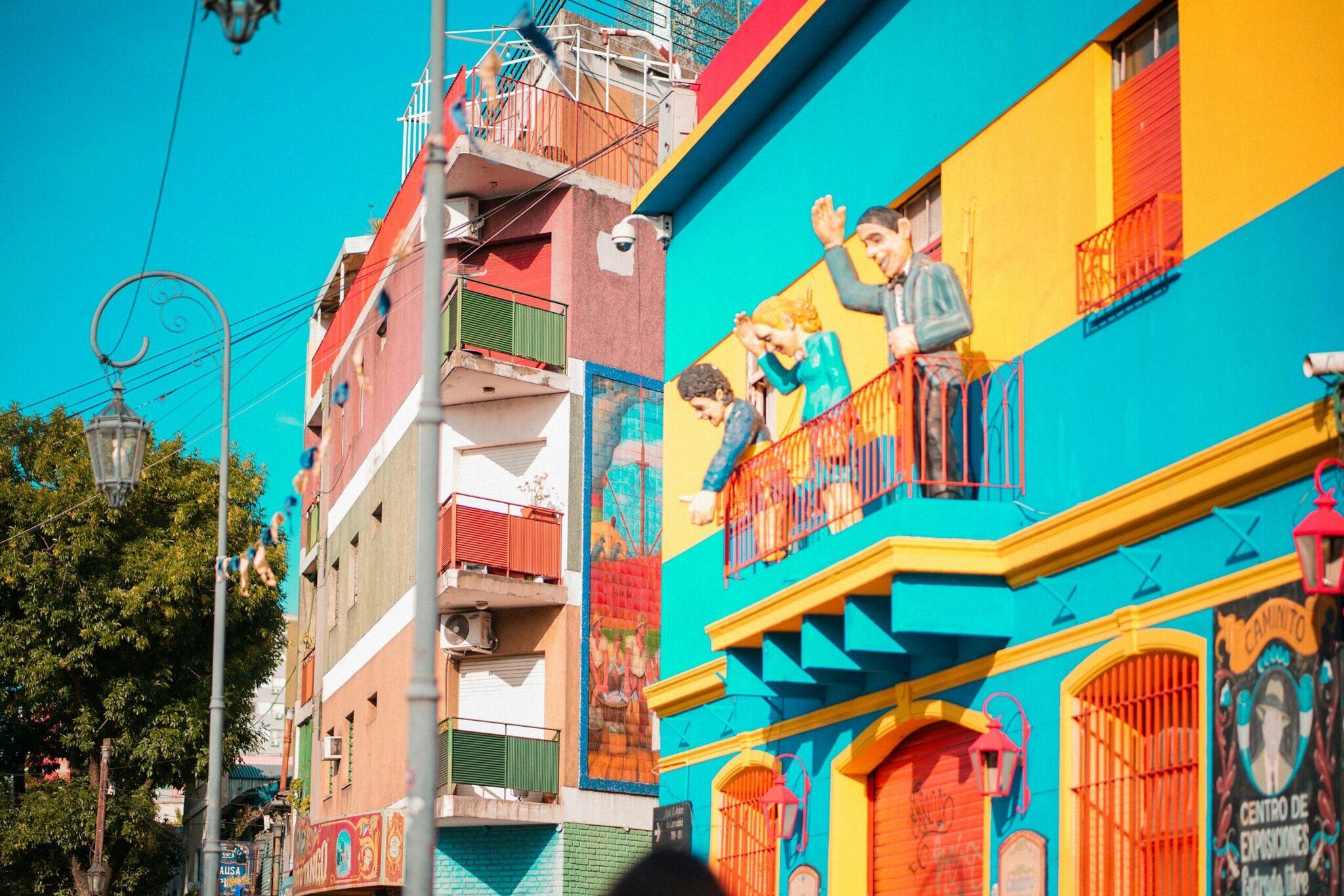 Facciata colorata con edifici gialli, blu e rossi ornati da murales che rappresentano bambini in gioco