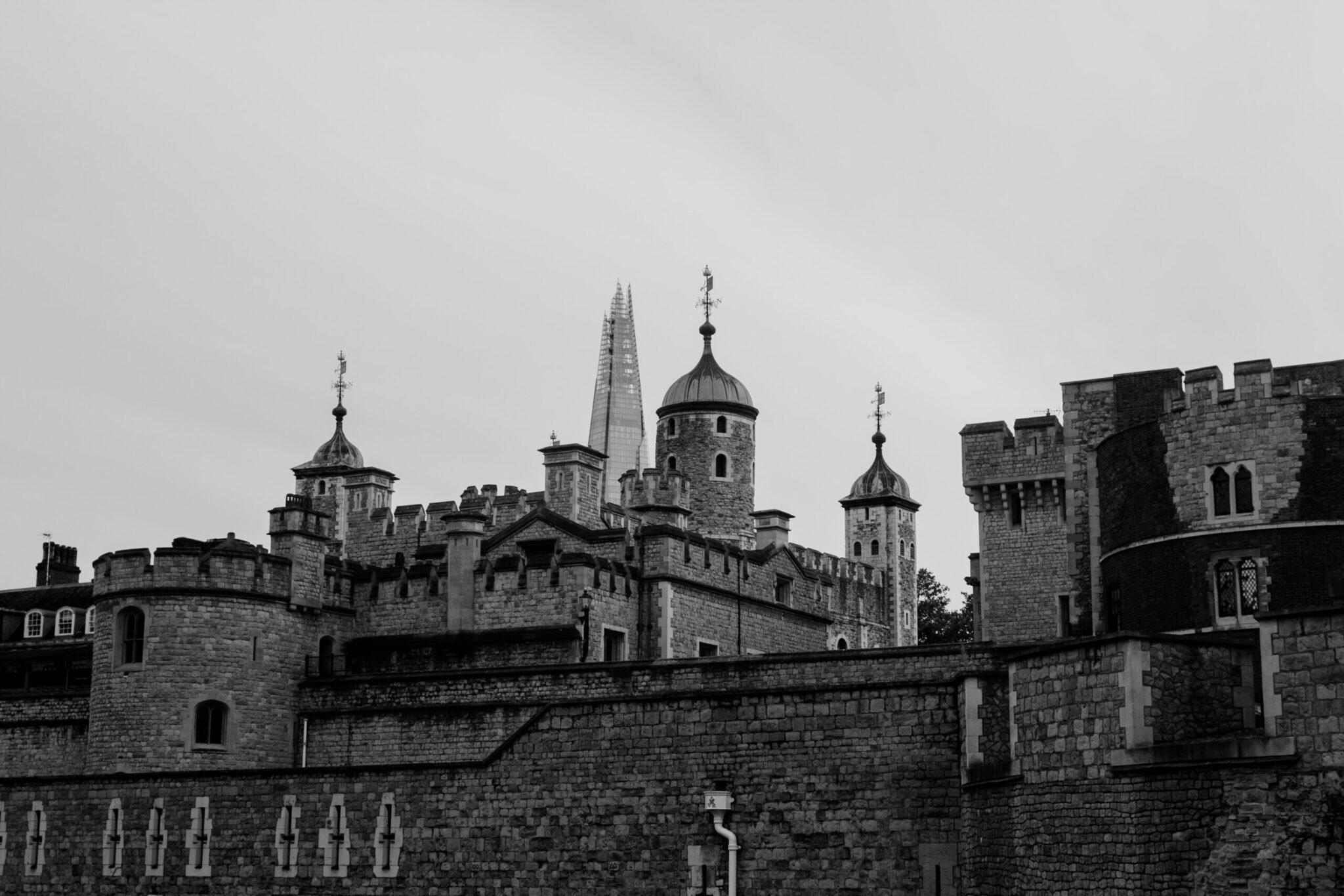 Fortaleza medieval de piedra con torres almenadas y cúpulas, fotografiada en blanco y negro bajo un cielo nublado