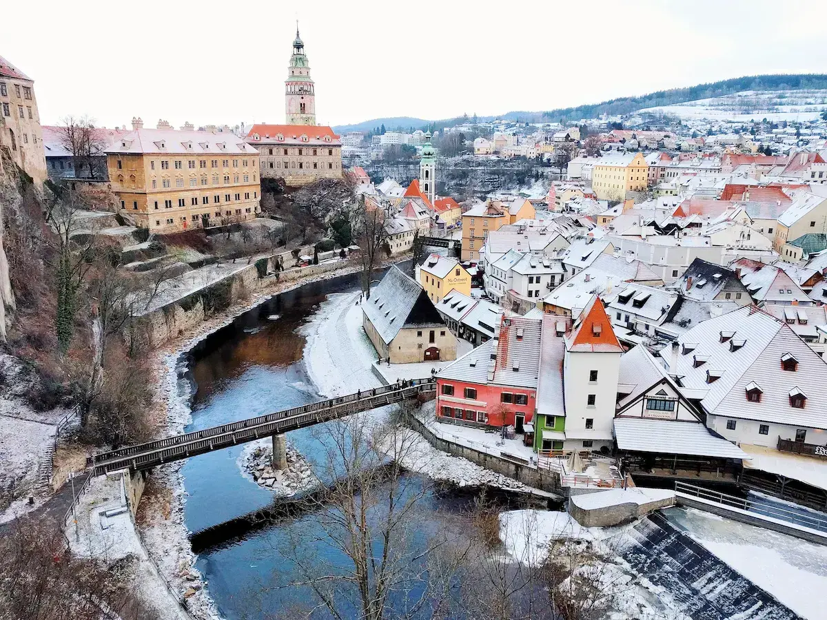Vista panorámica de una ciudad de Europa Central con río, castillo medieval y tejados nevados en invierno