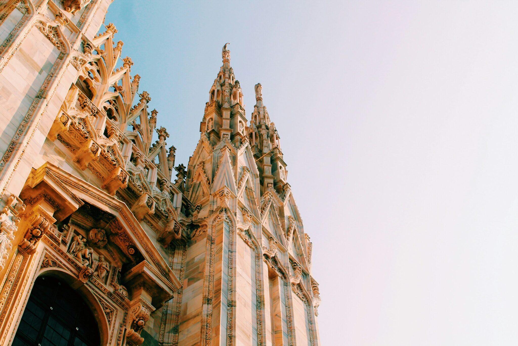 Architektonisches Detail einer gotischen Kathedrale mit verzierter Fassade und spitzen Fialen unter wolkenlosem Himmel