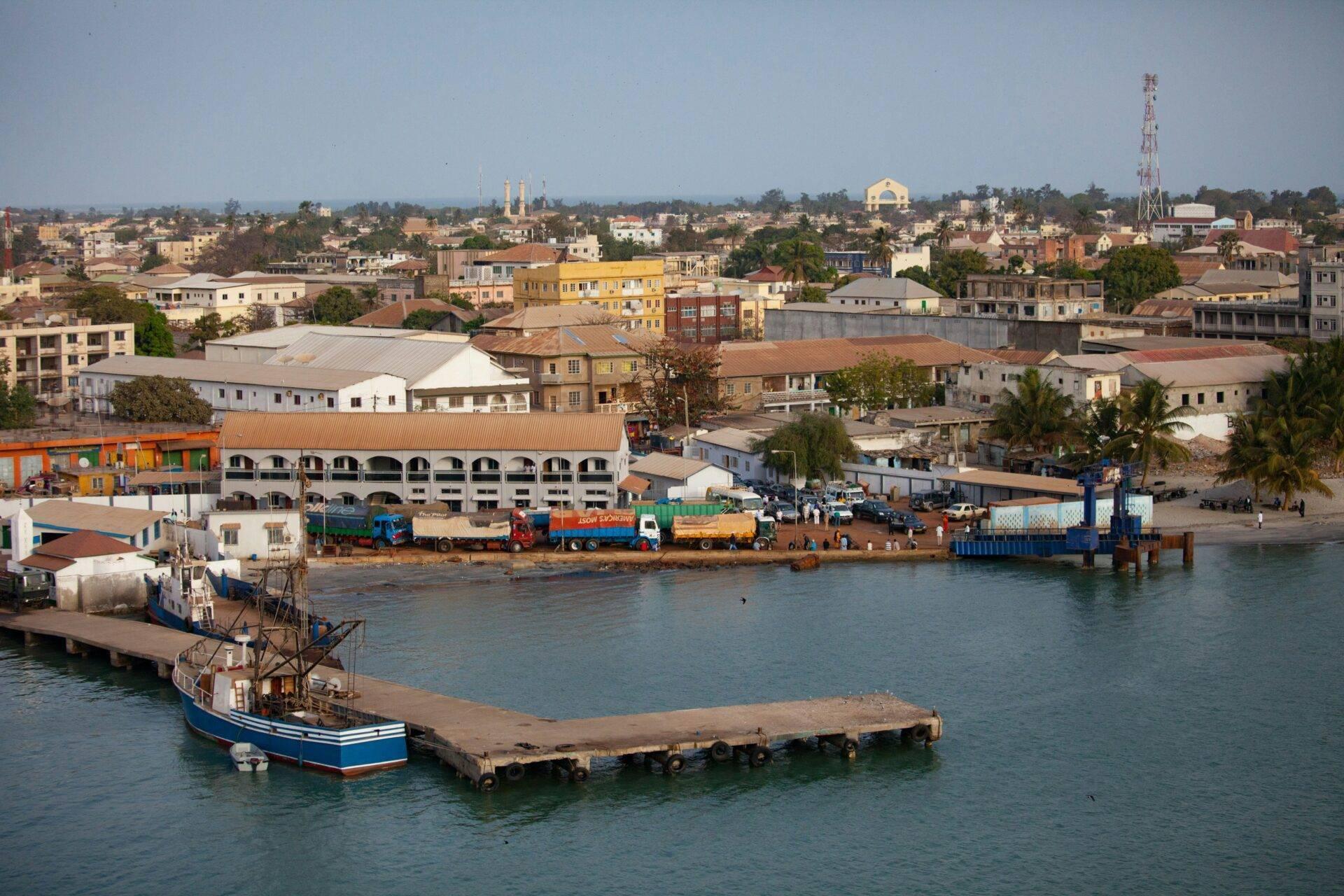 Panoramablick auf einen afrikanischen Flusshafen mit Booten, bunten Lagerhäusern und der dahinter liegenden Stadt