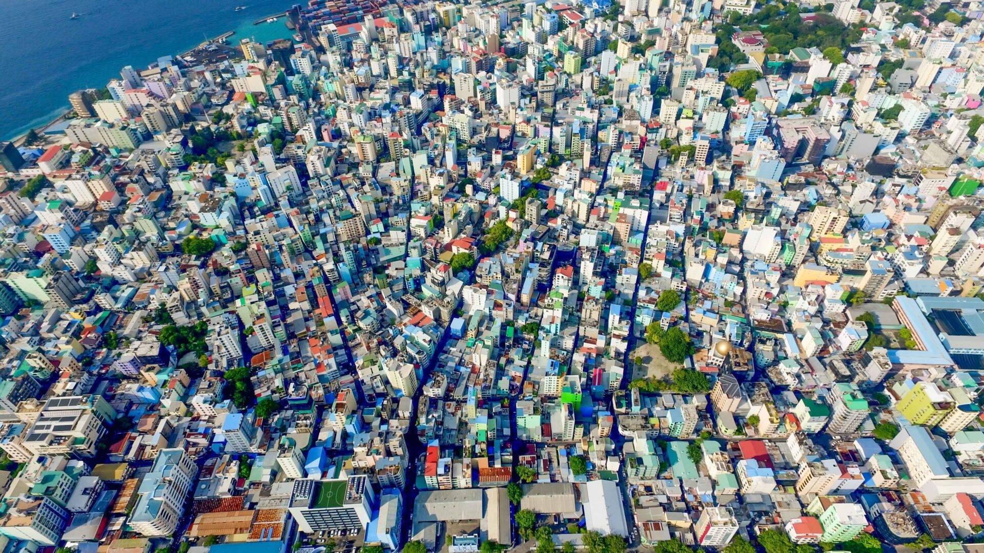 Vista aerea di una città costiera densamente costruita con edifici colorati e mare turchese sullo sfondo