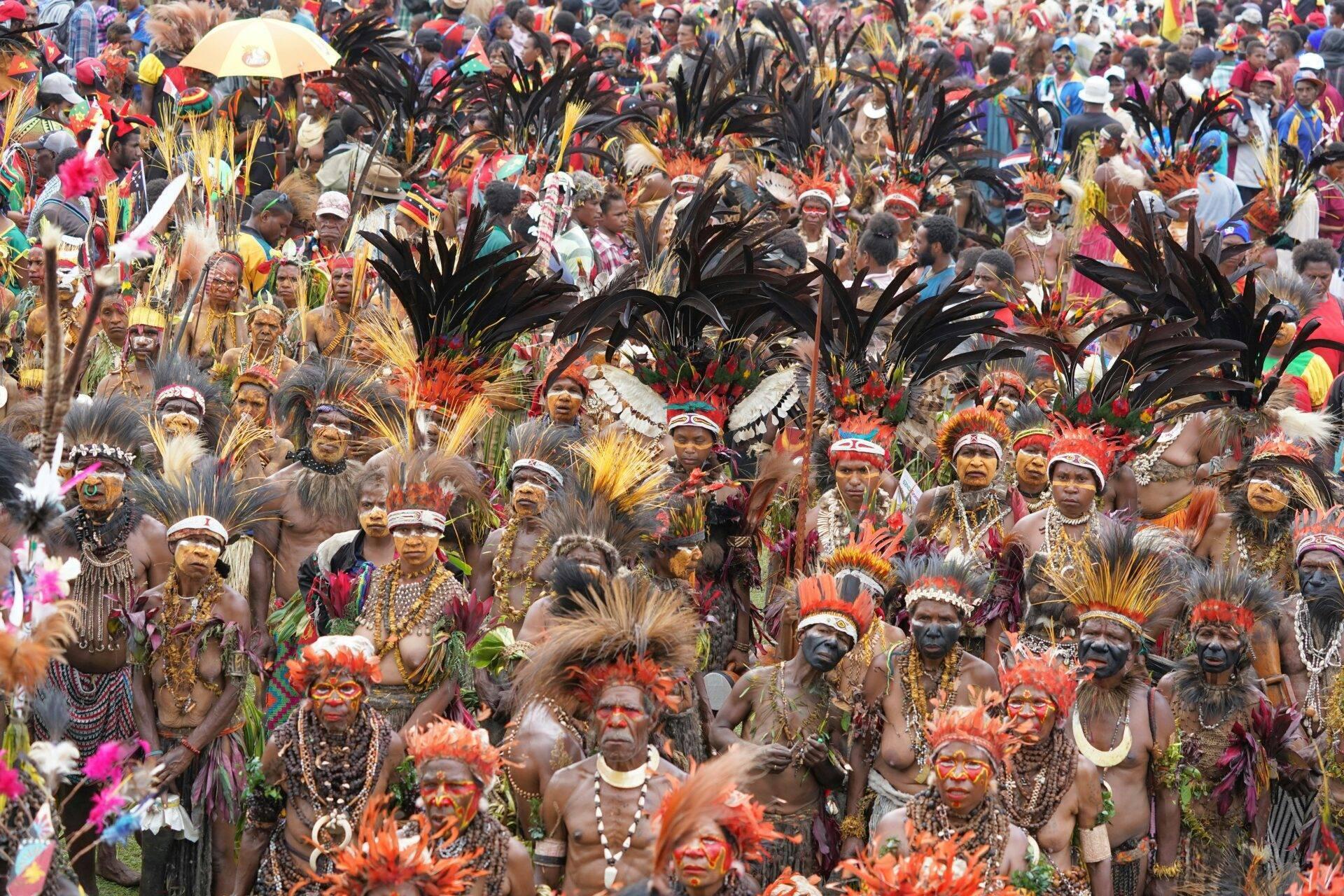 Folla densa di partecipanti in costumi colorati con piume e dipinti sul viso a un festival culturale tropicale