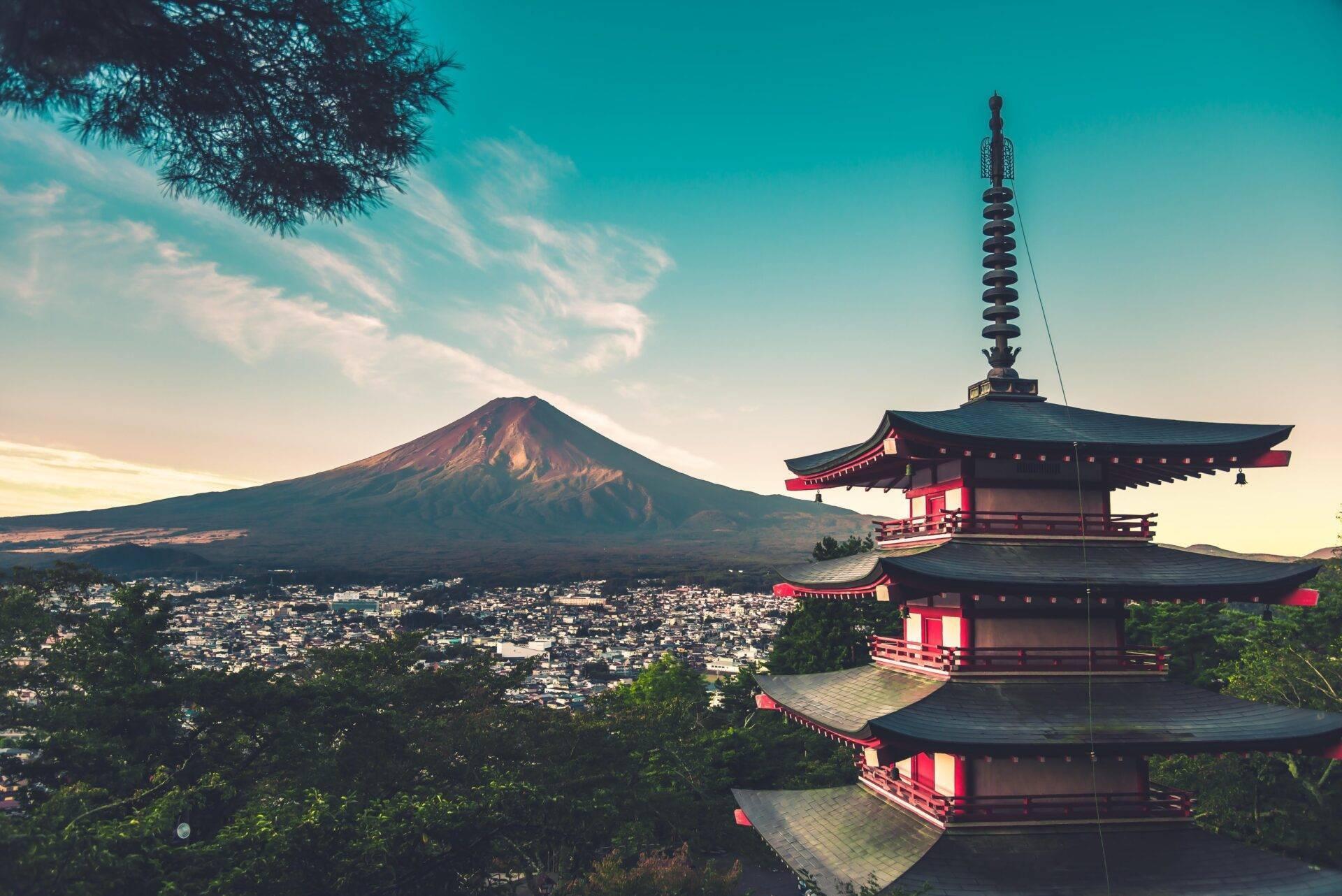 Panoramablick auf den Fuji mit einer traditionellen roten japanischen Pagode im Vordergrund und der weitläufigen Stadt darunter