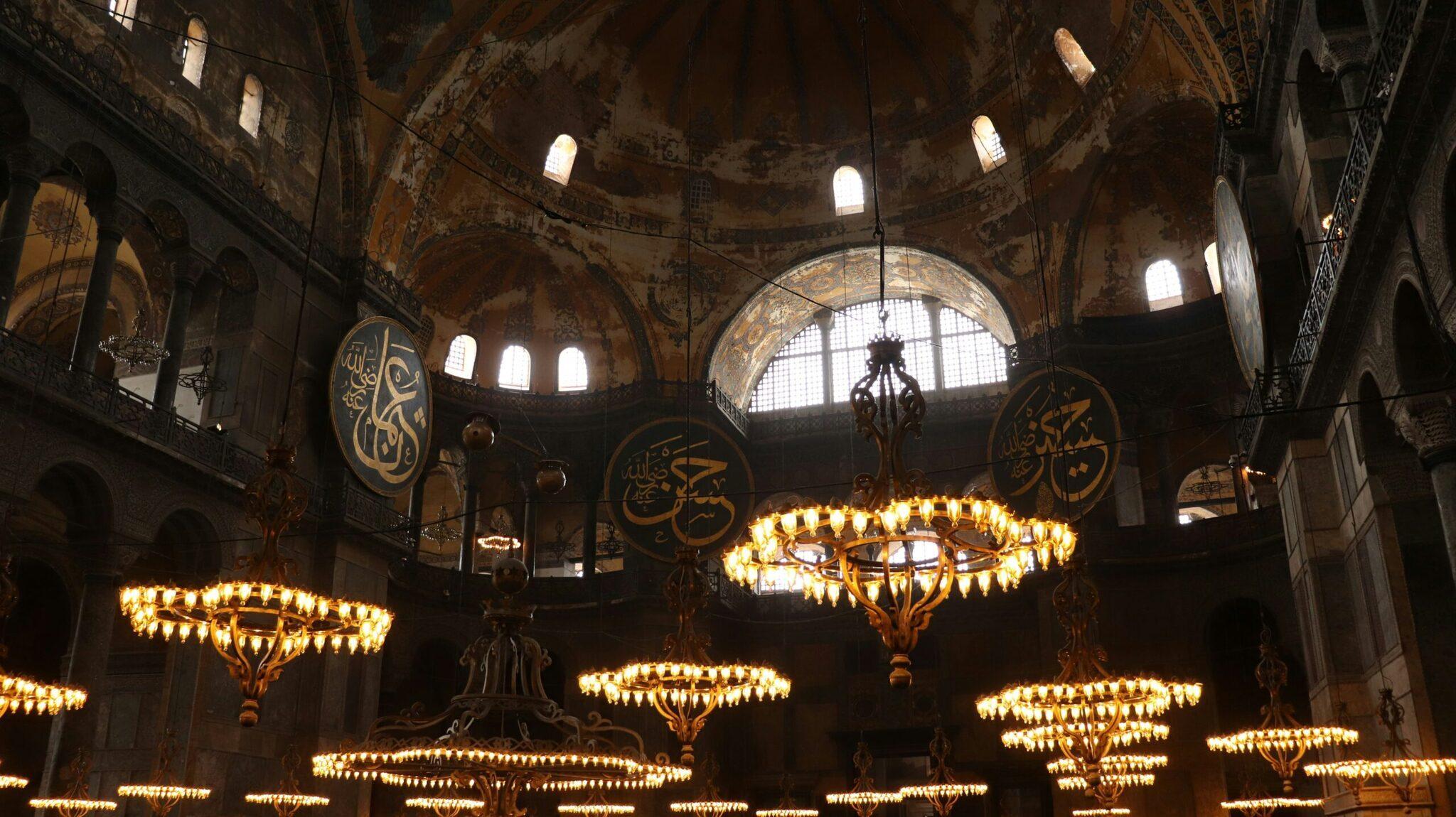 Interno maestoso di una moschea con cupola, calligrafie dorate e lampadari illuminati