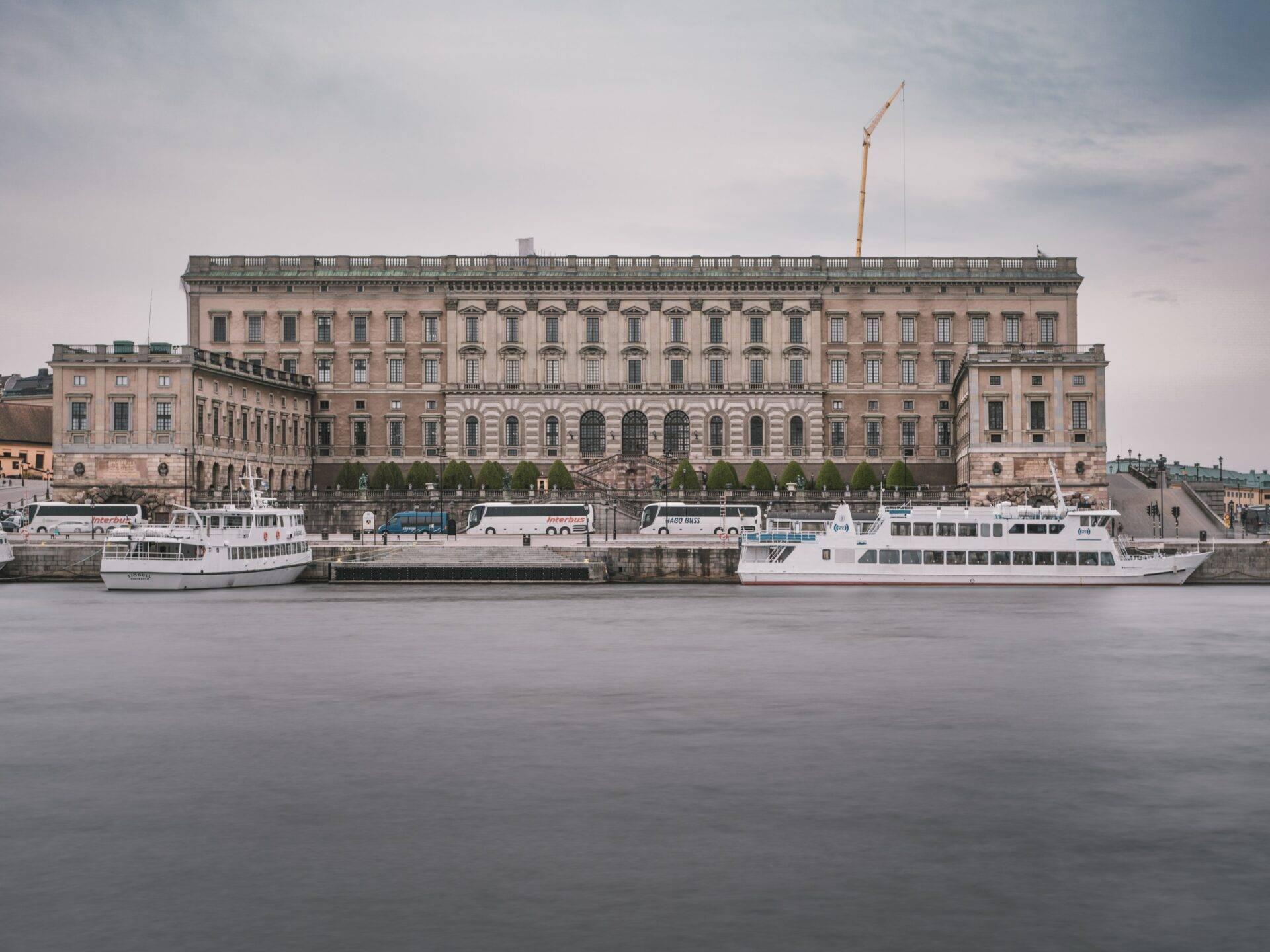 Rosafarbener Königspalast am ruhigen Wasser mit zwei festgemachten Touristenbooten in der Nähe