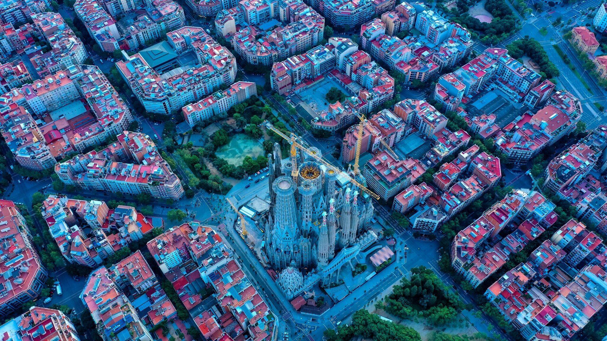 Vista aérea de la Sagrada Família rodeada de edificios residenciales con tejados rojos en un centro urbano europeo