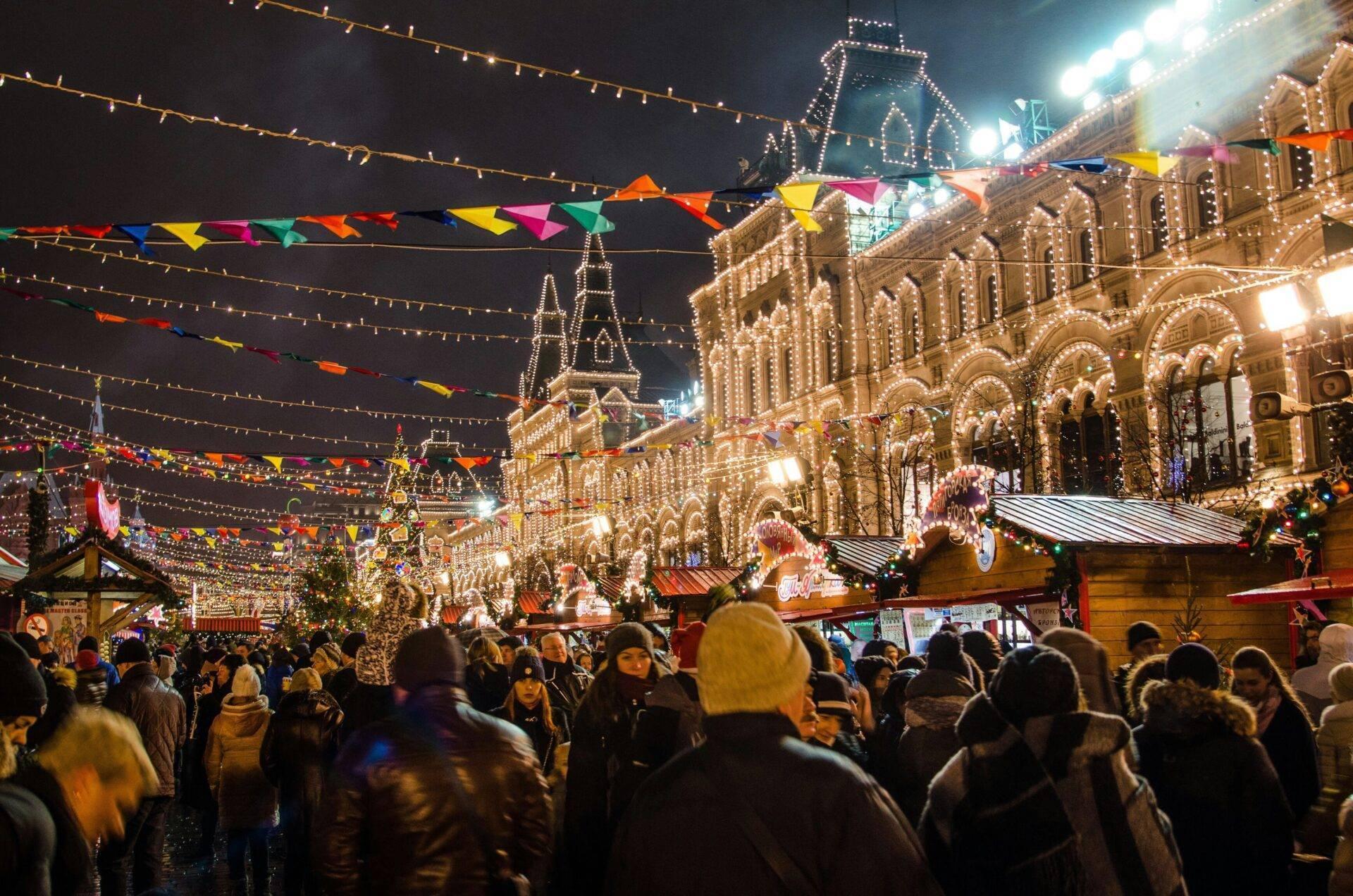 Beleuchteter nächtlicher Weihnachtsmarkt mit festlich dekorierten historischen Gebäuden, fröhlichem Treiben und bunten Lichterketten