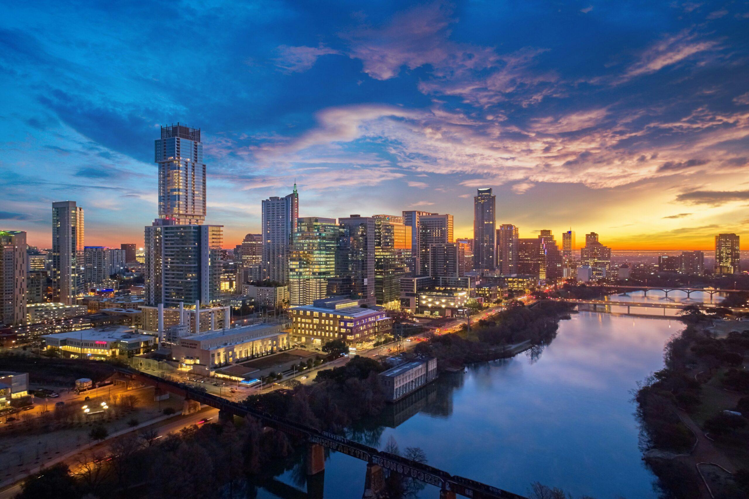Skyline einer amerikanischen Großstadt im Abendlicht, Wolkenkratzer spiegeln sich im ruhigen Fluss
