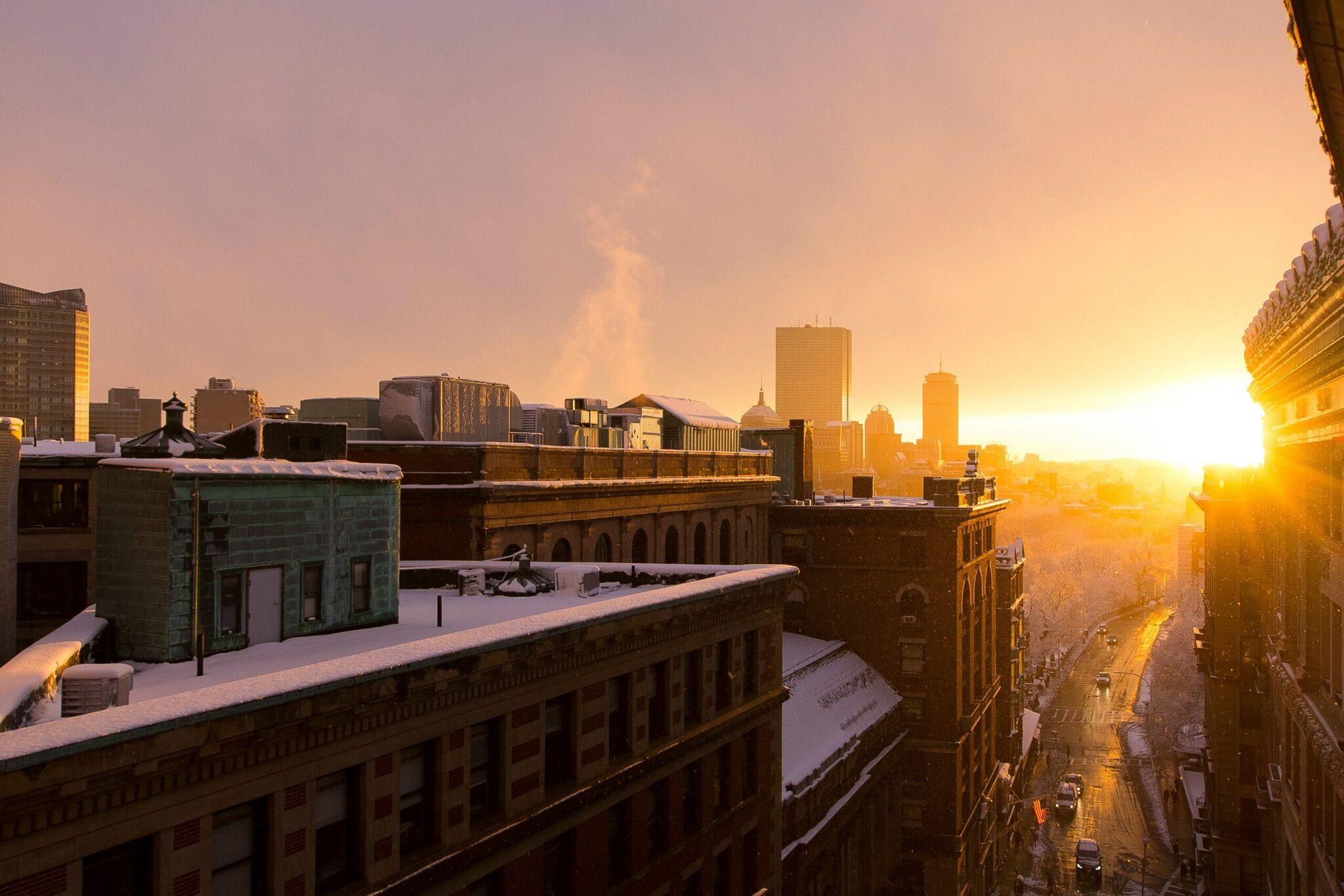 Aerial view of a snow-dusted city at sunset with historic buildings and modern skyscrapers in the background