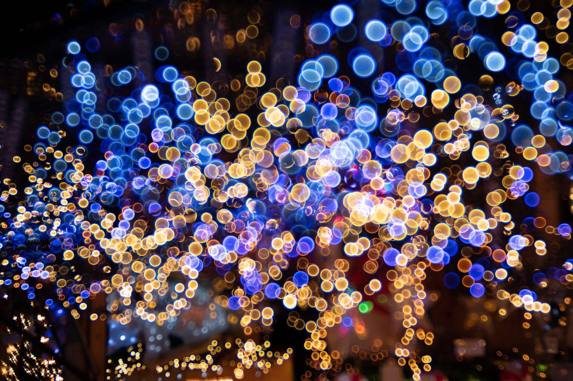 Decoración navideña festiva con cientos de bolas brillantes azules, doradas y blancas suspendidas en la noche