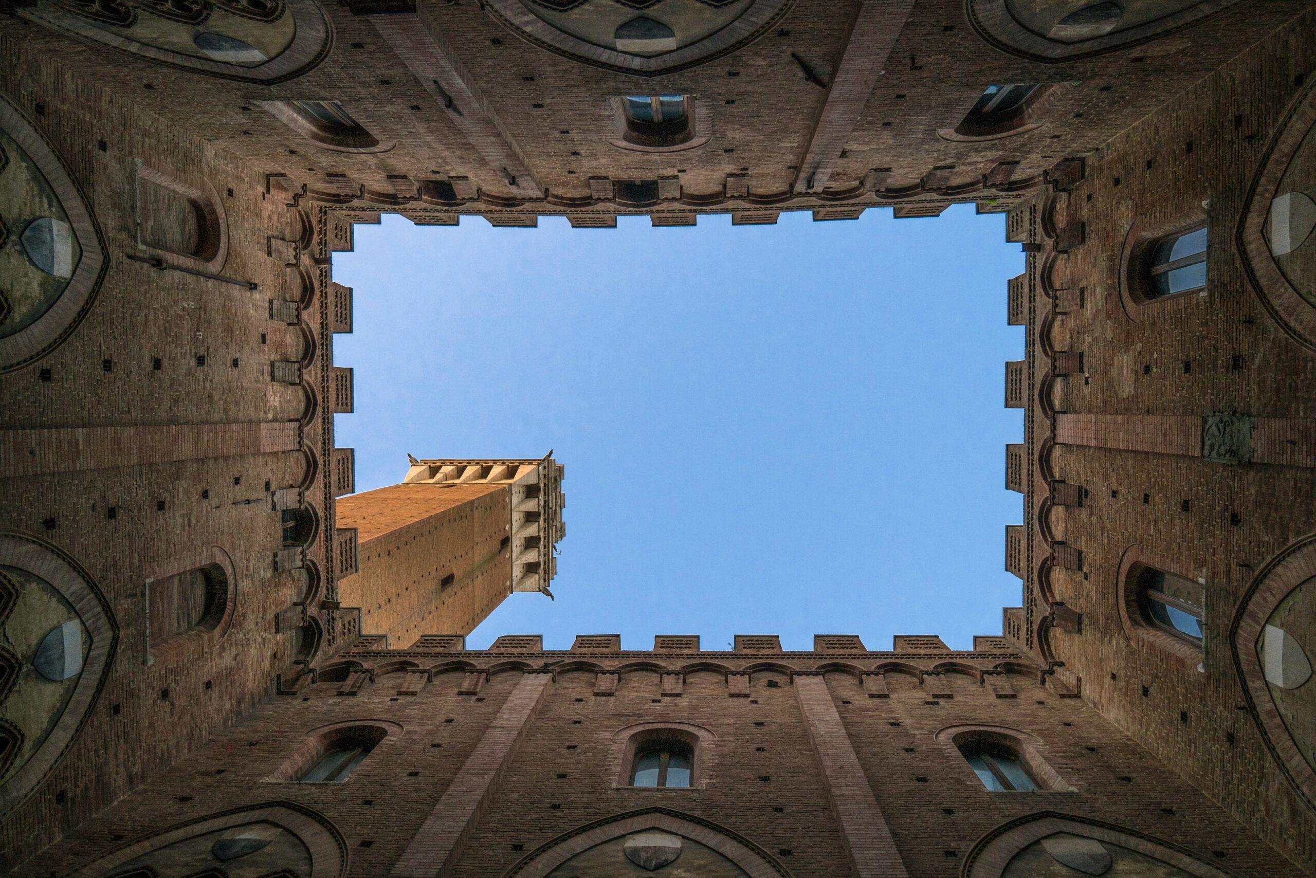 Vista en contrapicado del patio interior de un palacio medieval italiano de ladrillo con cielo azul