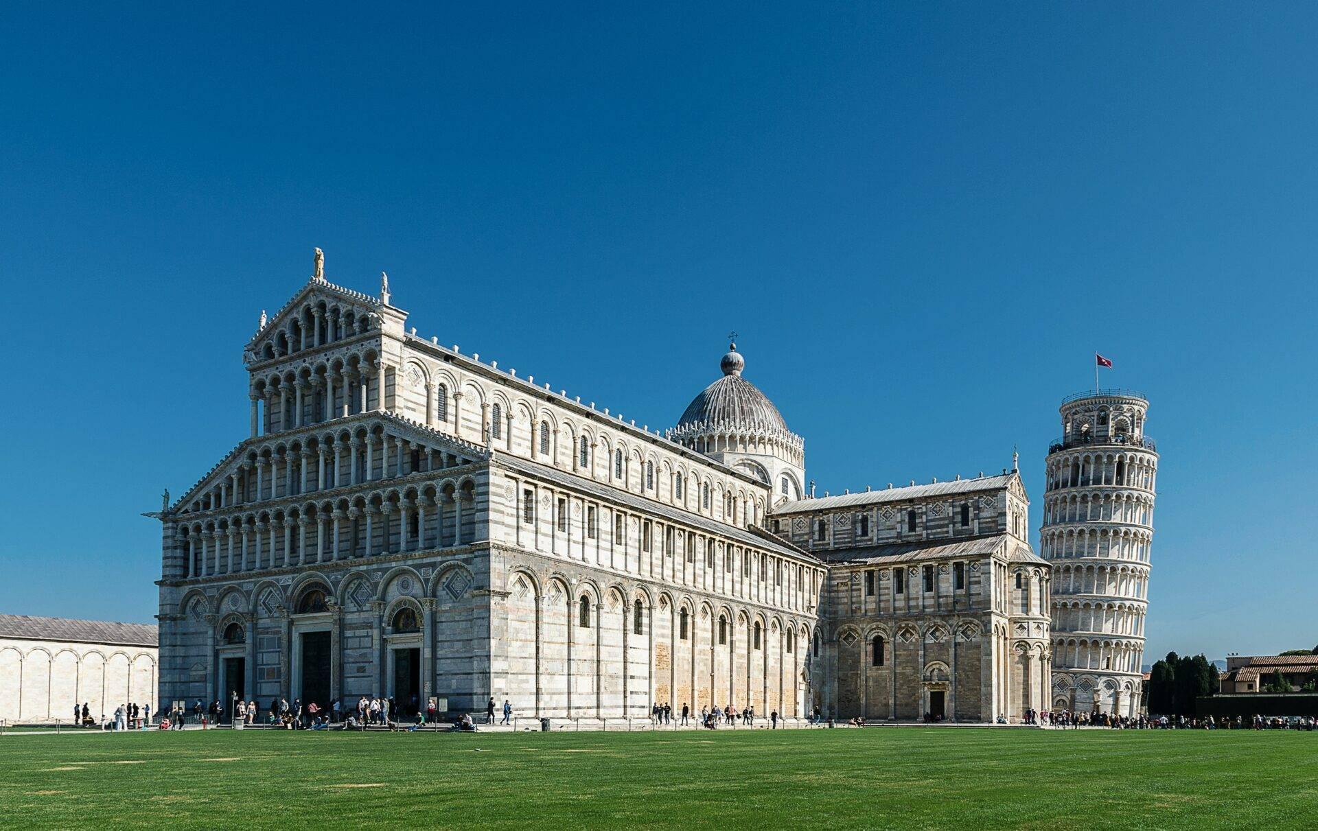 Pisa Cathedral with its famous leaning tower in the Piazza dei Miracoli under a clear blue sky