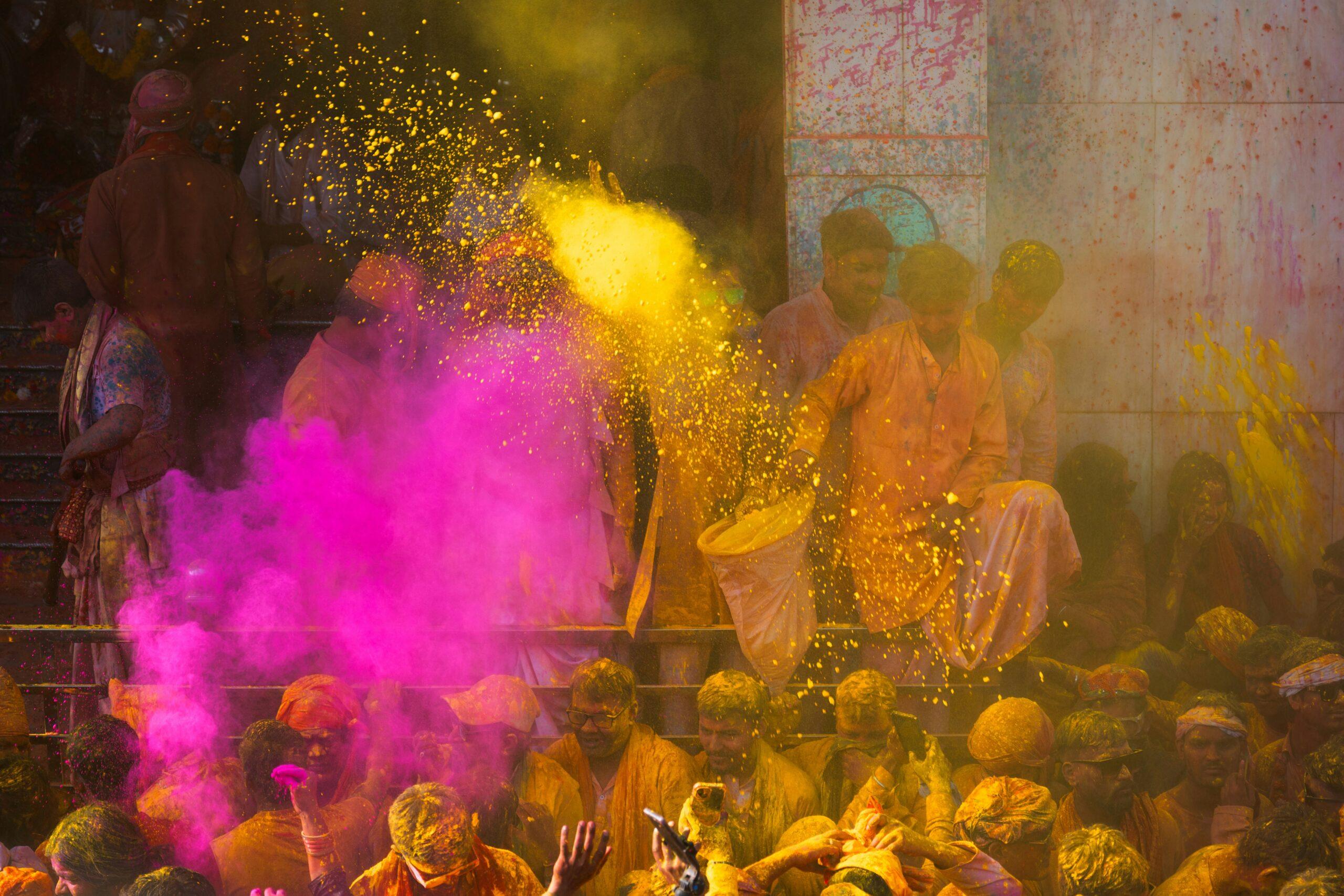 Holi festival in India: clouds of coloured powder and jubilant crowds under a bright blue sky